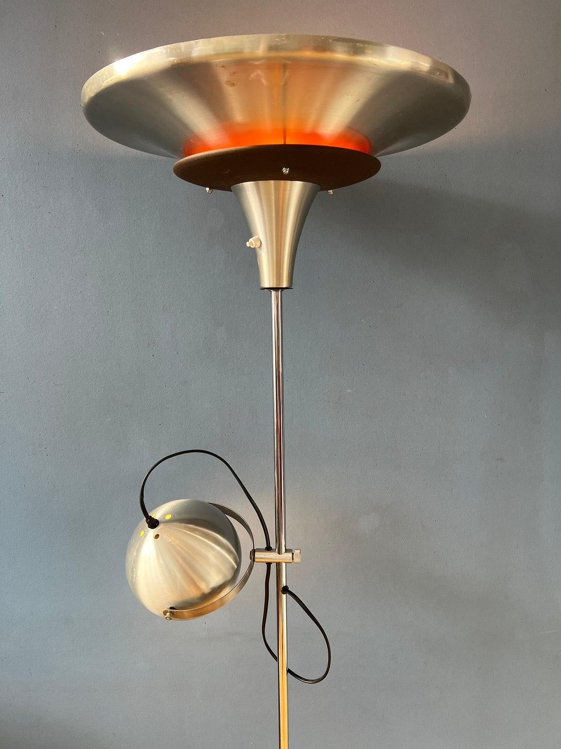 Vintage Lakro Amstelveen space age floor lamp with UFO-shaped shade. On the side the lamp has a small eyeball light. The lamp is made out of metal and aluminium, combining colours of silver, orange and white. The lamp requires two E27 lightbulbs and