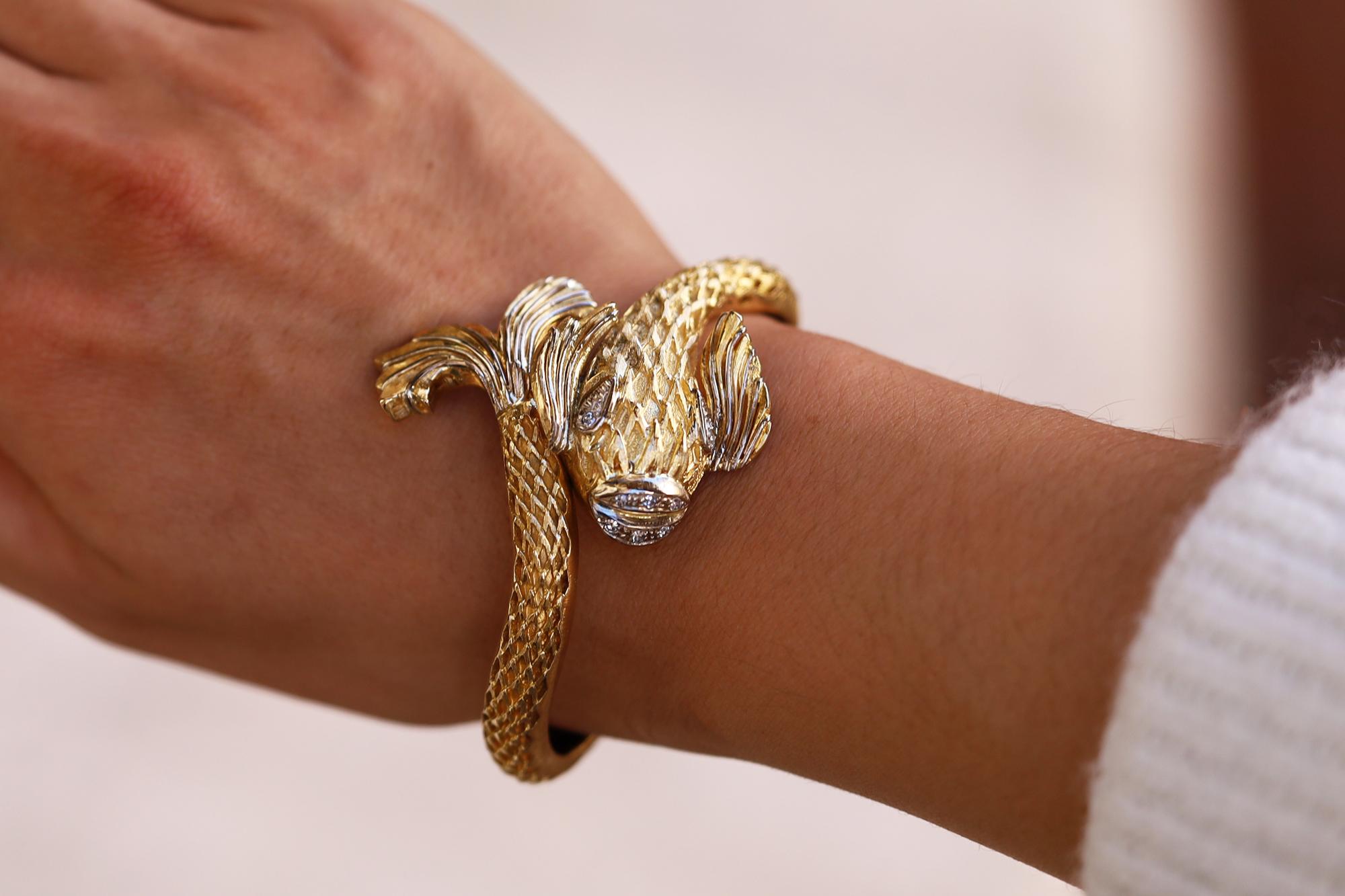 A classic and iconic bracelet from noted jeweler Ilias Lalaounis, this 18kt gold and diamond bangle features a swimming koi or Siamese fighting fish wrapping around itself. The hinged cuff sits beautifully on your wrist and is easily worn as a