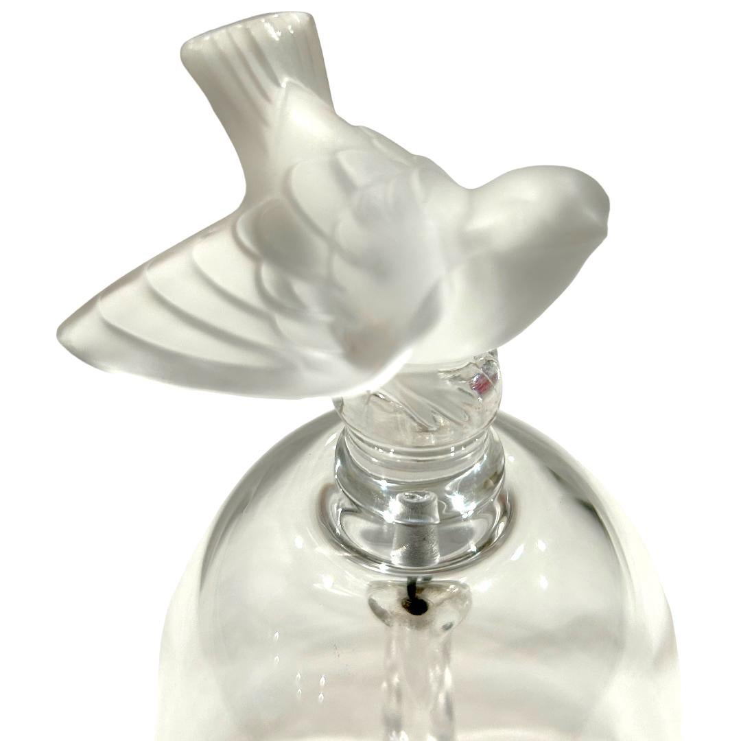 Cette cloche en cristal signée Lalique avec une poignée en forme de moineau givré est un ajout unique à toute collection.  Fabriquée avec précision, la cloche met en valeur la beauté complexe du cristal.  La poignée, en forme de moineau, ajoute une