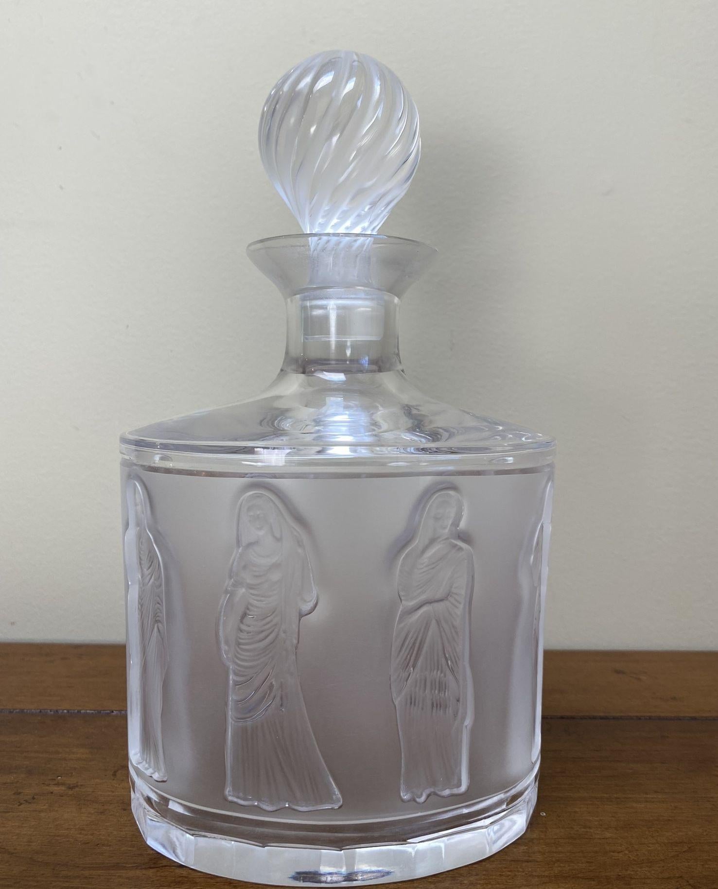 Simply Beautiful! Lalique France Antique Women Crystal Whisky Decanter. Featuring Women dressed in Togas autour folded into the crystal surface. Measuring approx. 9. 5” x 5.5” MARKINGS: signed on flat-cut base, Lalique France. 32.12 oz. Volume;