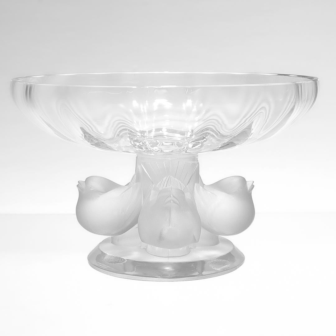 A fine Lalique compote or footed bowl.

In the Nogent pattern (or Sparrows design). 

With a frosted finish pedestal and base supporting a transparent scalloped bowl.

Designed by Marc Lalique in 1969.

Bearing an etched 'Lalique' signature to the