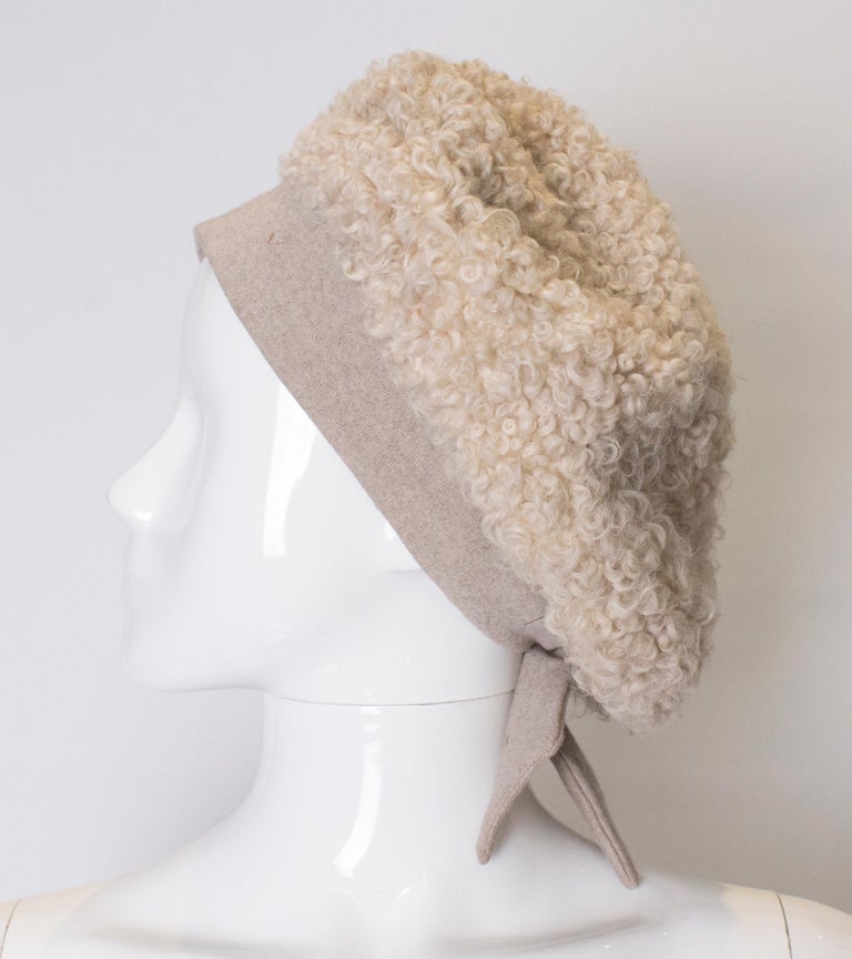 A cut beret for Spring. The crown is lambswool in a beige colour. It has a matching hat pin, and bow at the back of the band. Inner circumference 25''