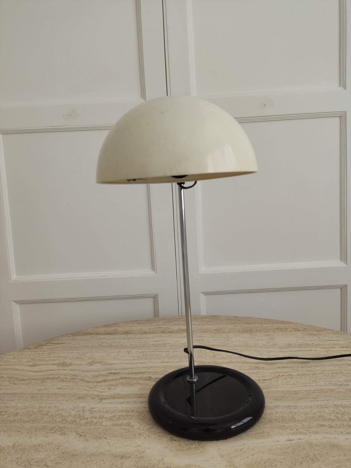 This luminaire consists of a height-adjustable reflector that swivels 360 degrees. The stem and the base are metallic. The light diffuser is made of plastic. The electrical wiring is integrated inside the metal rod which is fixed to the base of the