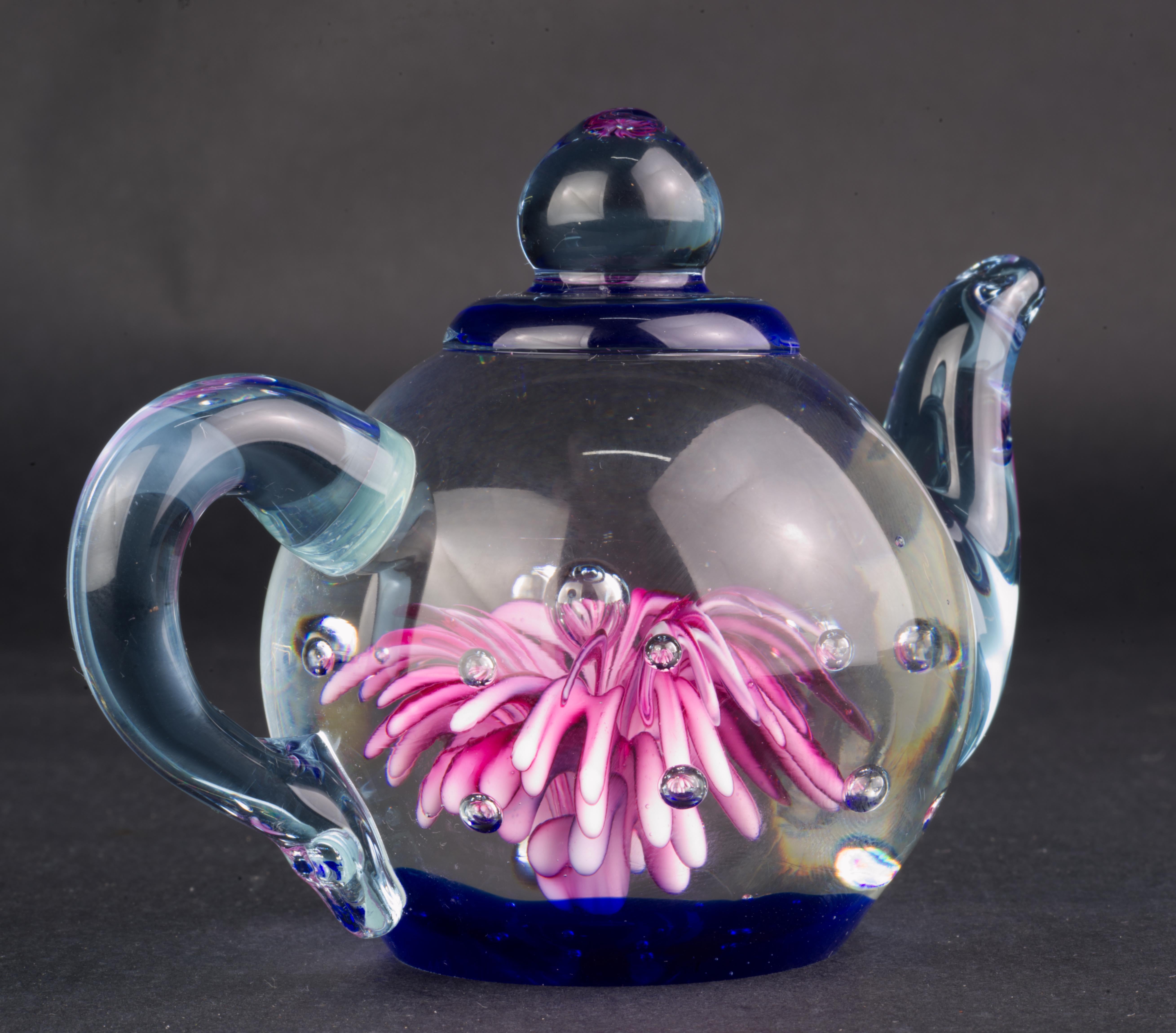 Der verspielte Briefbeschwerer in Form einer Teekanne ist in Sommerso-Technik hergestellt; farbiges Glas wird in Pigmente getaucht und mit klarem Glas überfangen. Kontrollierte Luftblasen verleihen dem Stück Lebendigkeit und Bewegung und heben das