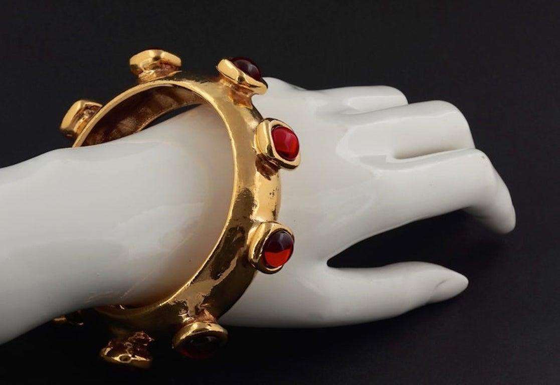 Vintage LANVIN PARIS Protruded Cabochon Gear Bangle Bracelet

Measurements:
Height : 6/8 inch
Inner Dimension: 2 5/8 inches

Features:
- 100% Authentic LANVIN PARIS.
- Protruding red glass cabochons in the form of mechanical gear.
- Gold tone.
-