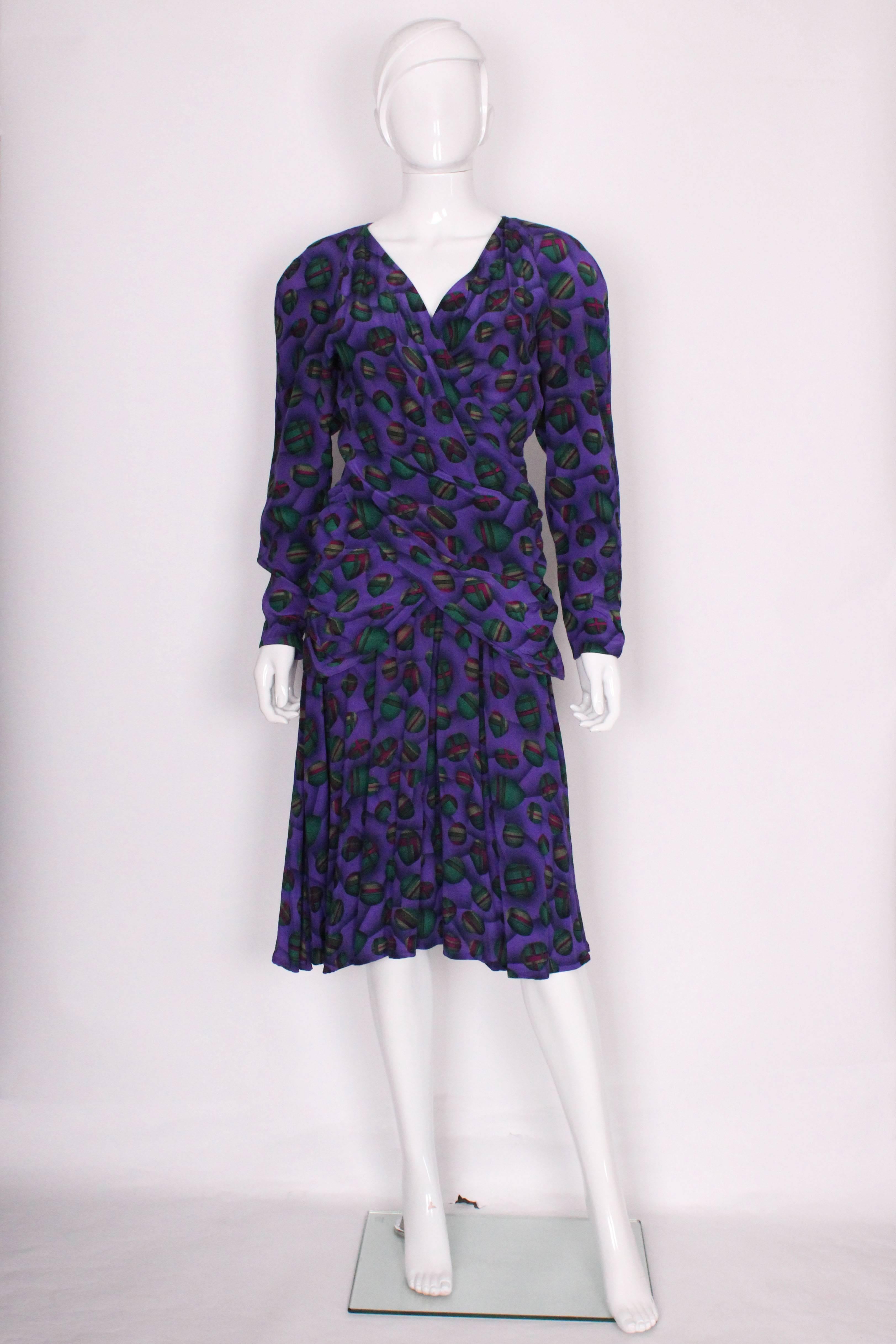 A chic and easy to wear dress by French design house,Lanvin. In a wonderful silk, with a purple background, with a green , red and cream deign.The dress has a v neck with a cross over front and gathered skirt.The dress has a central back zip.