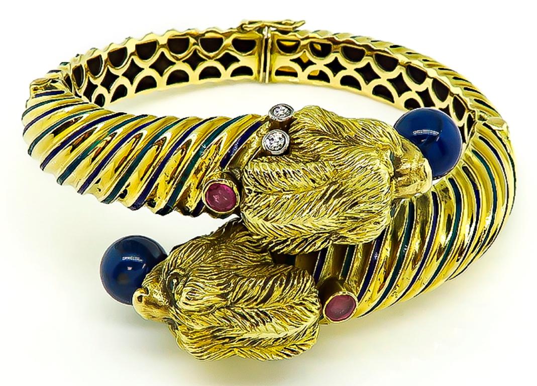 This fabulous 18k yellow gold lion's head bangle from the 1960s. features lovely lapis, ruby and diamond accents. The bangle is stamped 18k and weighs 75.3 grams. The top of the the bangle measures 33mm by 48mm. It will fit a standard wrist