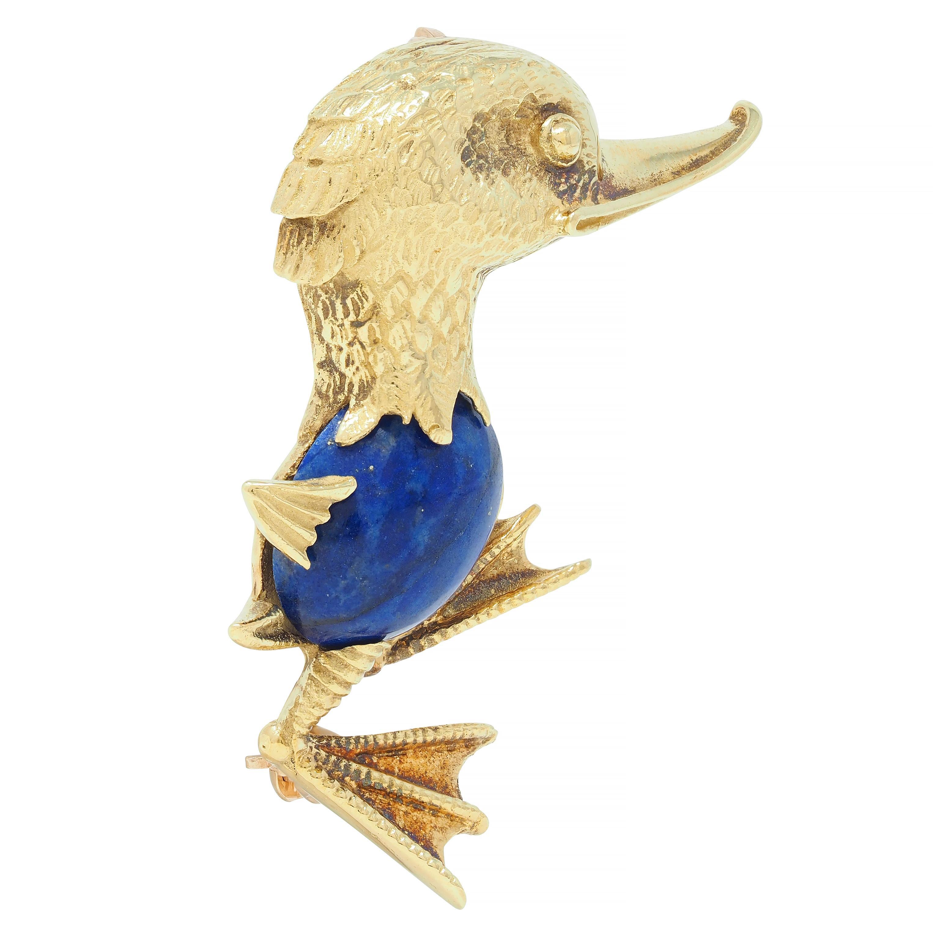 Designed as a stylized, whimsical duck with a dimensional head and feet 
Grooved with smiling features and engraved with feather texture 
Centering an oval-shaped lapis lazuli cabochon - measuring 10.0 x 12.0 mm 
Opaque ultramarine blue in color