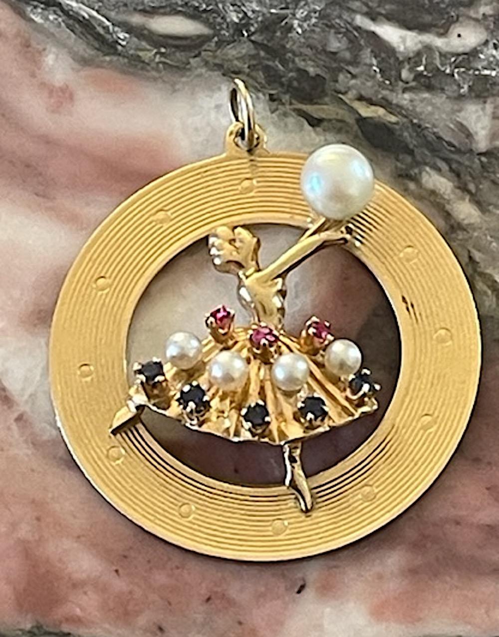 Engine turned discs are highly coveted. This fabulous vintage engine turned dancer charm is no exception. It's perfect for a long necklace chain or  hanging from a chic, statement charm bracelet.

14k Yellow Gold and set with pearls and blue and