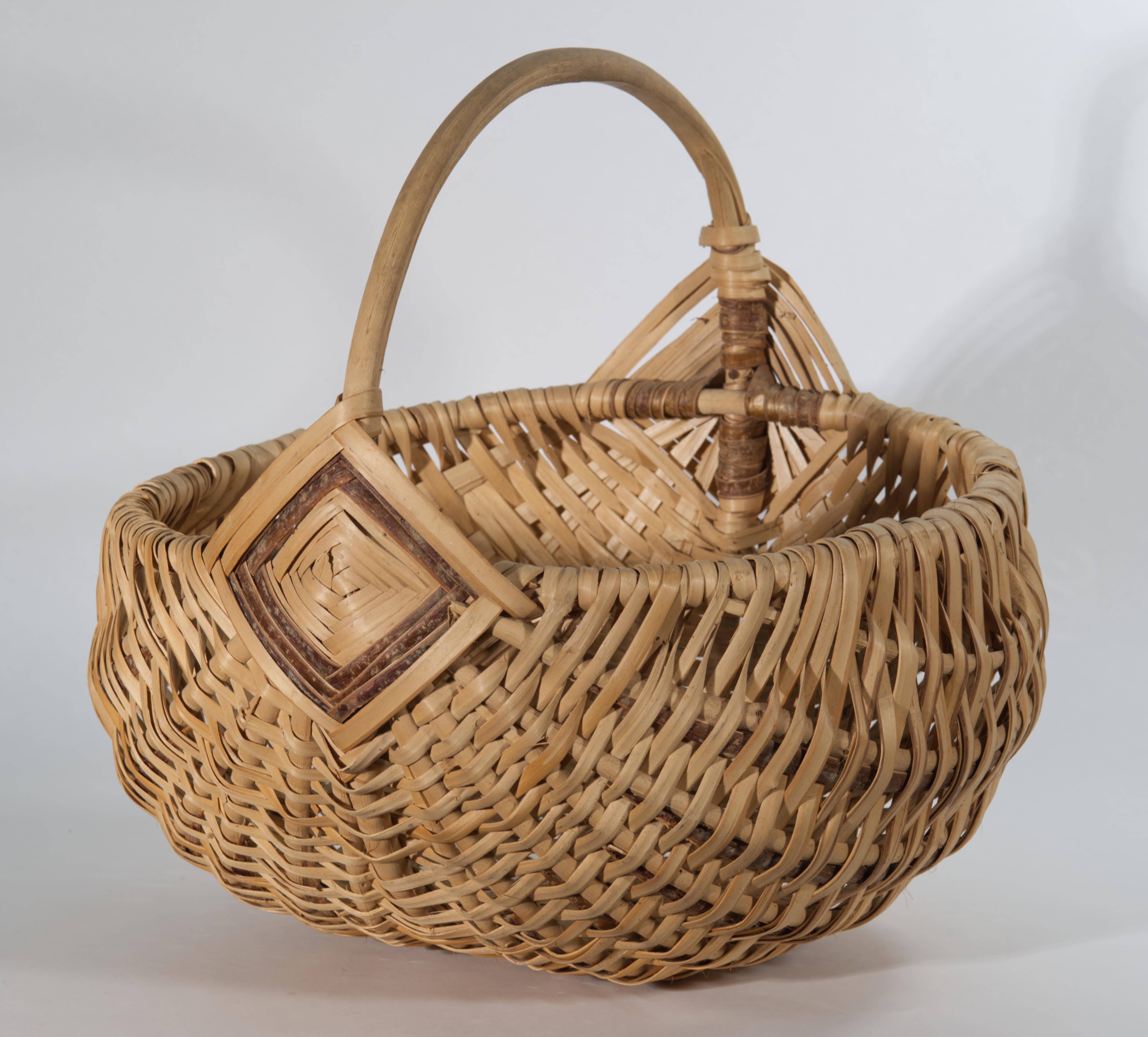 Vintage or antique oversized gathering basket features traditional rib or buttocks shape with the bent wood ring rim and handle. The plaited splints are carefully interwoven to carry the design along the body of the basket. The basket is decorated