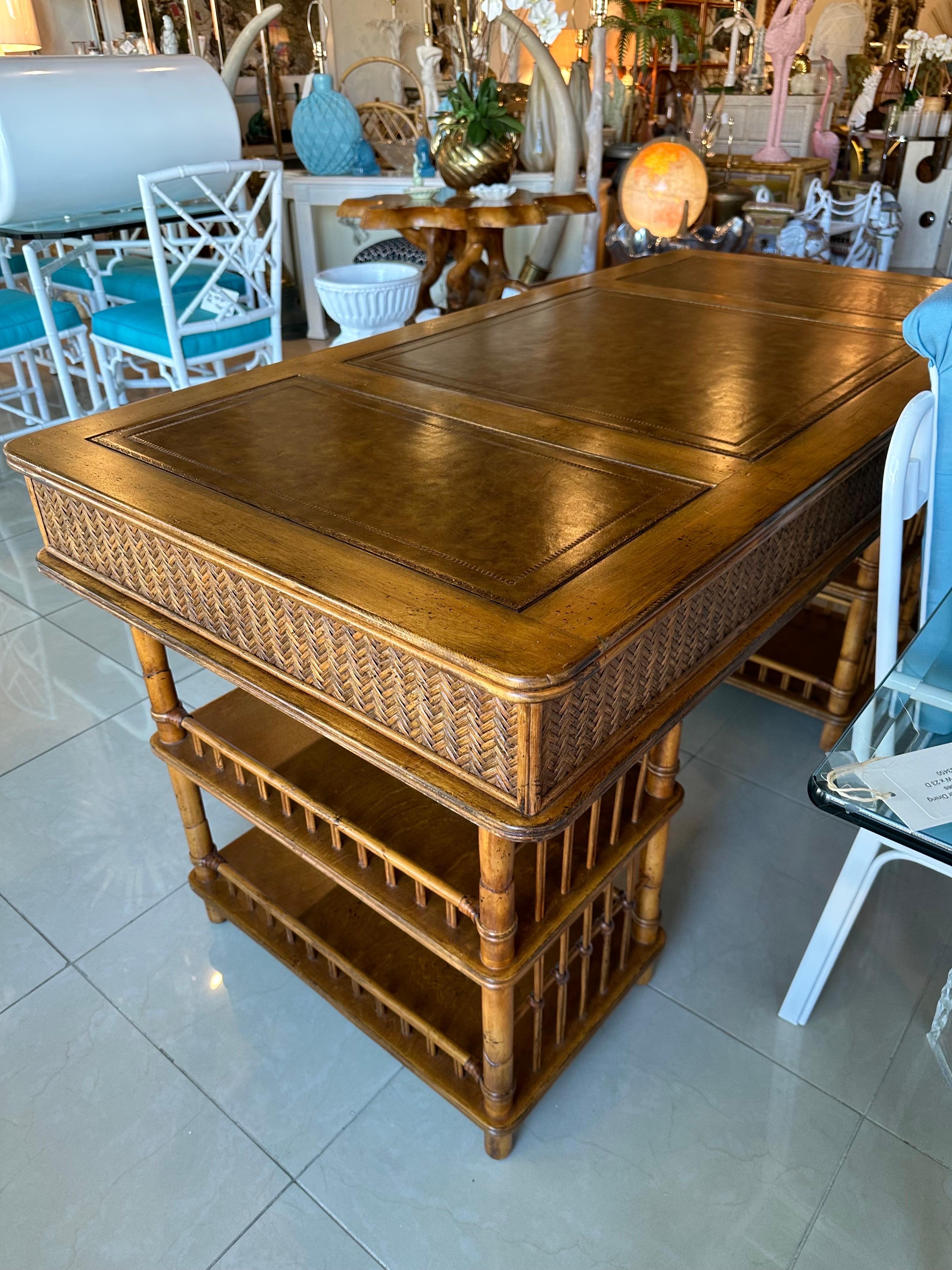 Lovely oversized bamboo, rattan and woven cane desk with large brass bamboo pull rings. Three drawers, double pedestals. The desk can flat in a room as all the sides, including the back are finished. A very few slight impressions on leather when the