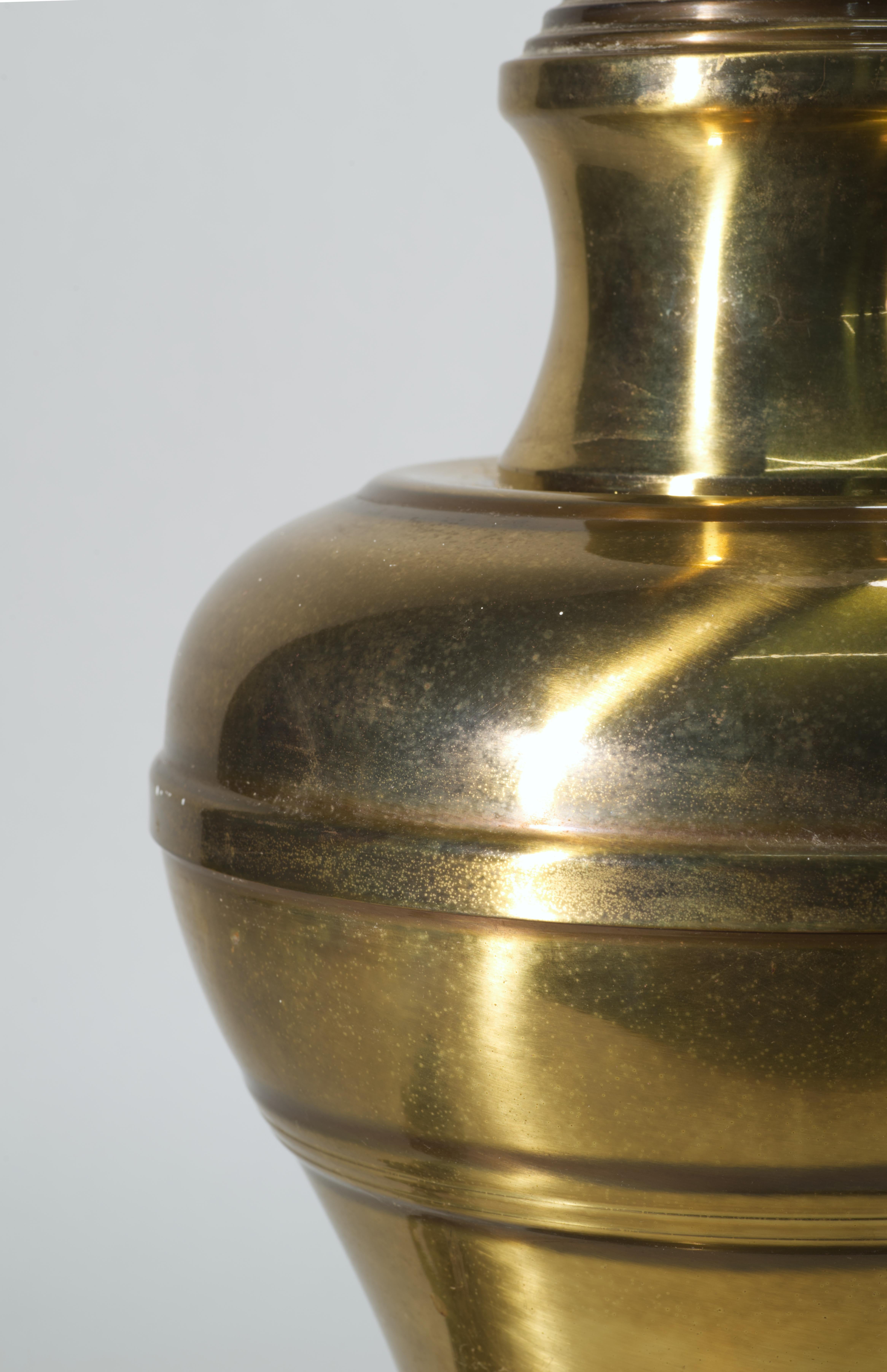 Large vintage brass ginger jar lamp has rounded body with minimal, traditional detailing and strong Chinoiserie style influence; it is mounted on stepped round base, creating a streamlined silhouette and allowing for a use of a wide range of