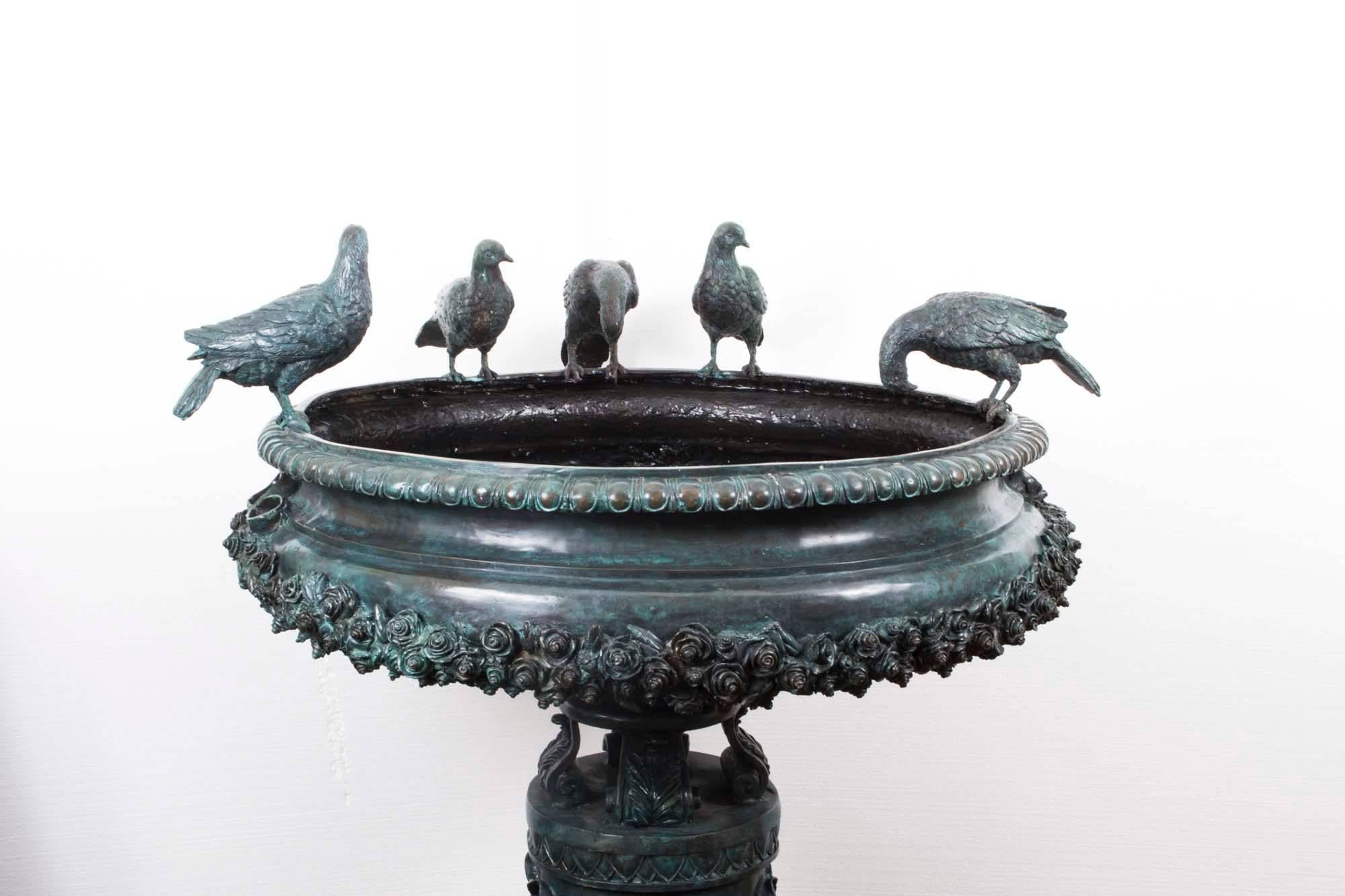 This is a stunning large fountain bird bath that is sculpted in solid bronze in the classical Greek style, and dates from the late 20th century.

The fountain features a large urn with exquisite decoration on a cylindrical plinth decorated with