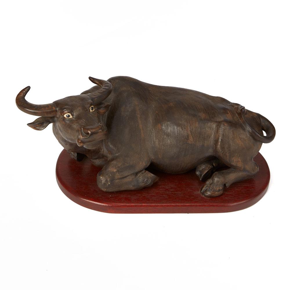 A large vintage Chinese pottery model of a recumbent water buffalo mounted on a wooden stand. The buffalo has a well detailed combed and slightly textured finish and decorated in naturalistic brown glazes with shaped and painted features. The