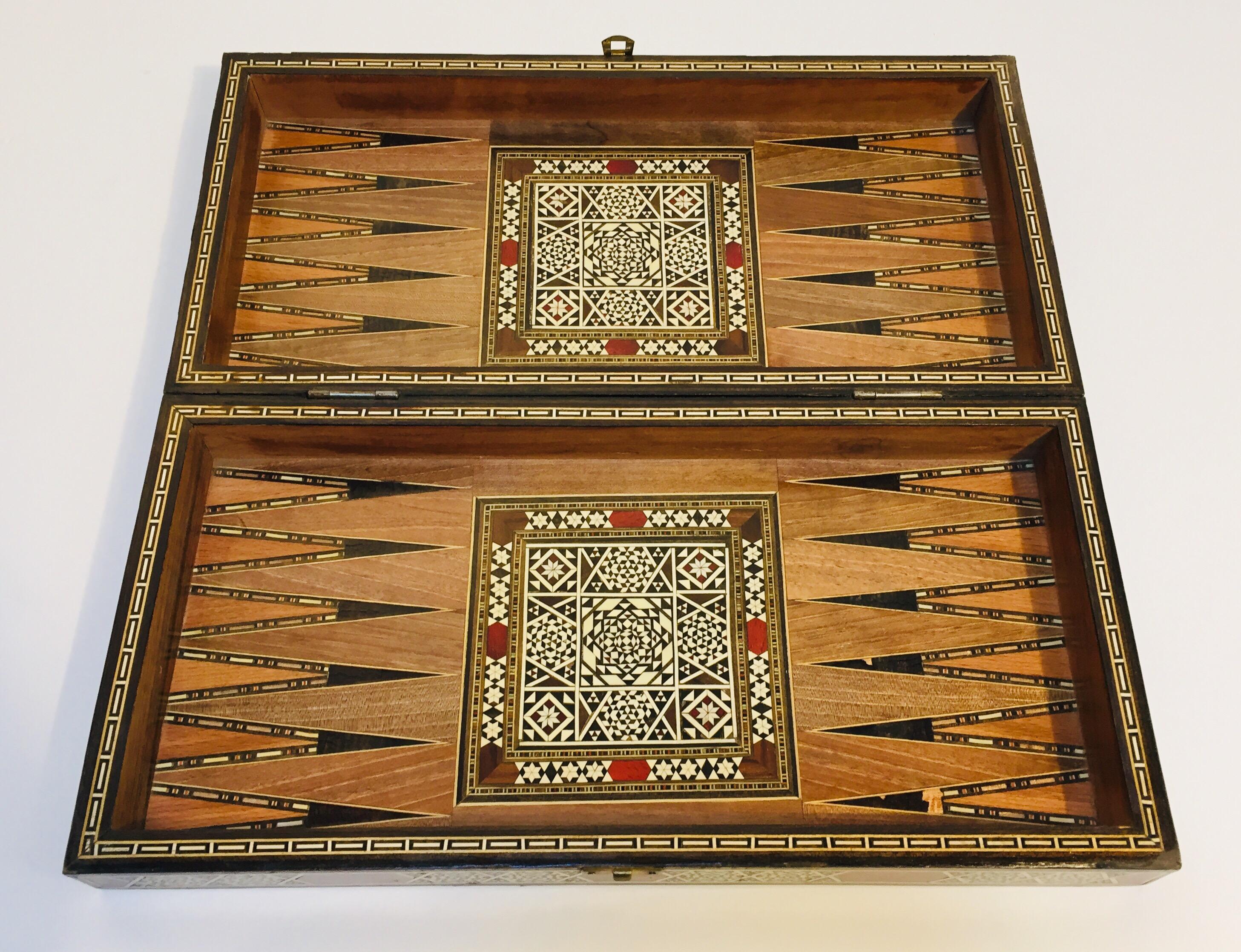 Large vintage midcentury Syrian inlaid mosaic backgammon and chess game.
Great inlaid micro mosaic hinged marquetry game box features a chess and checker board on the exterior and backgammon board on the interior with all the wooden dice and