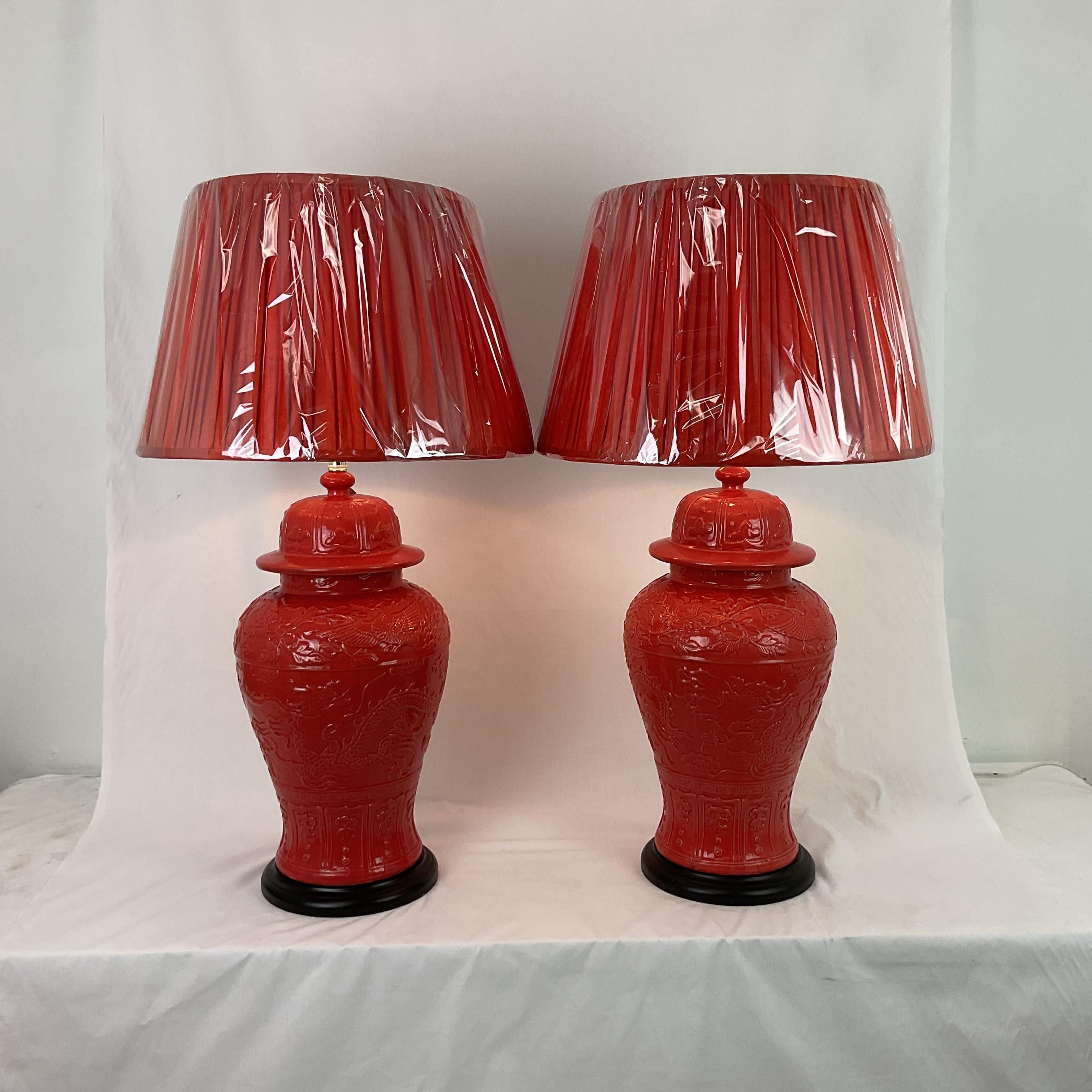 Incroyable paire de lampes à pot en gingembre asiatique à motif de dragon et de lotus. Magnifique glaçure orange corail brillante d'origine. Les bases en bois noir rehaussent la couleur. Abat-jour plissé en soie moirée, fait sur mesure, de 19
