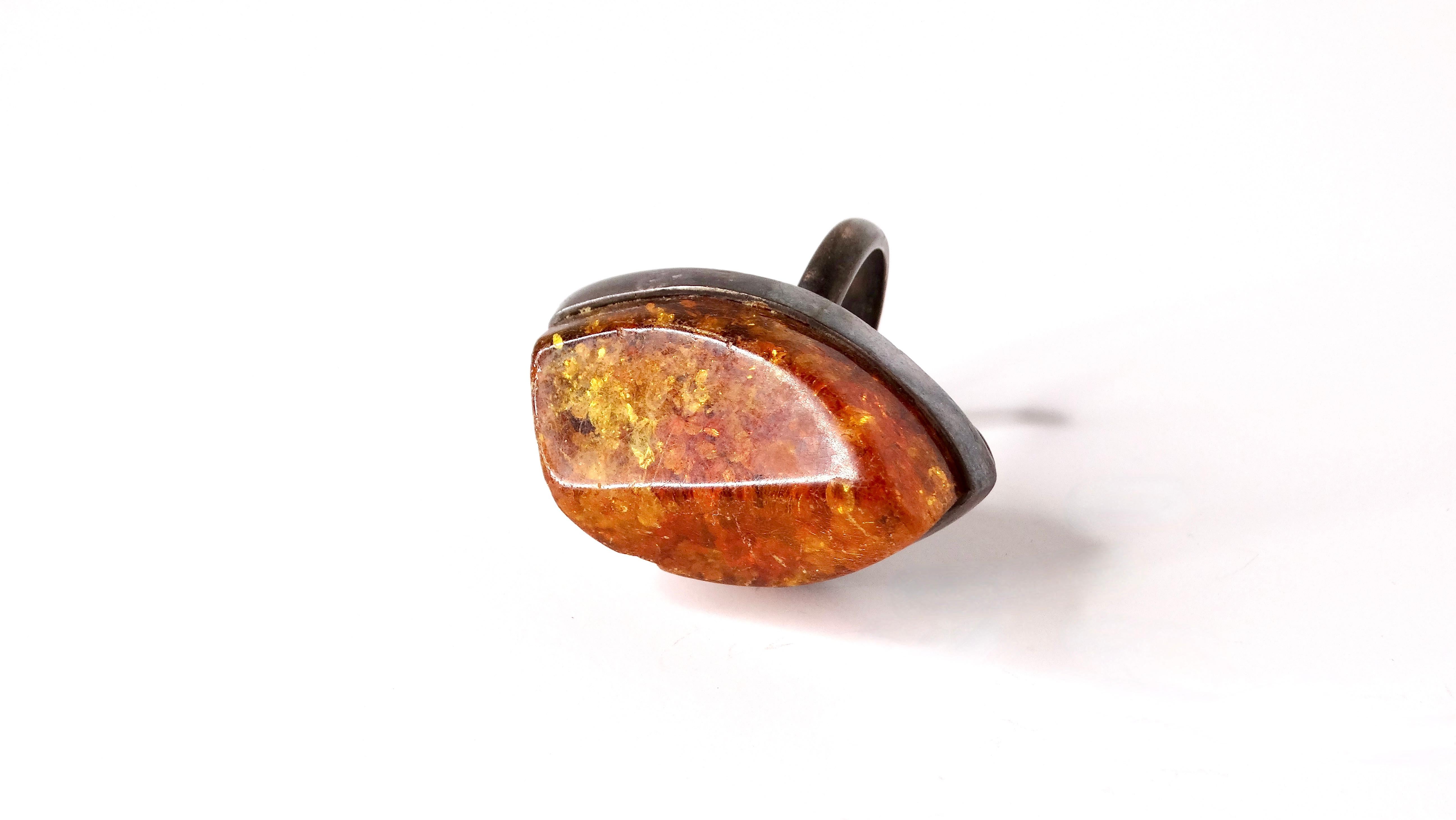 Introducing our Vintage Large Costume Polished Amber Metal Cocktail Ring, a stunning statement piece that embodies bold elegance. Crafted with a polished faux amber stone, this oversized ring sits on a beautifully designed mixed metal/brass band.