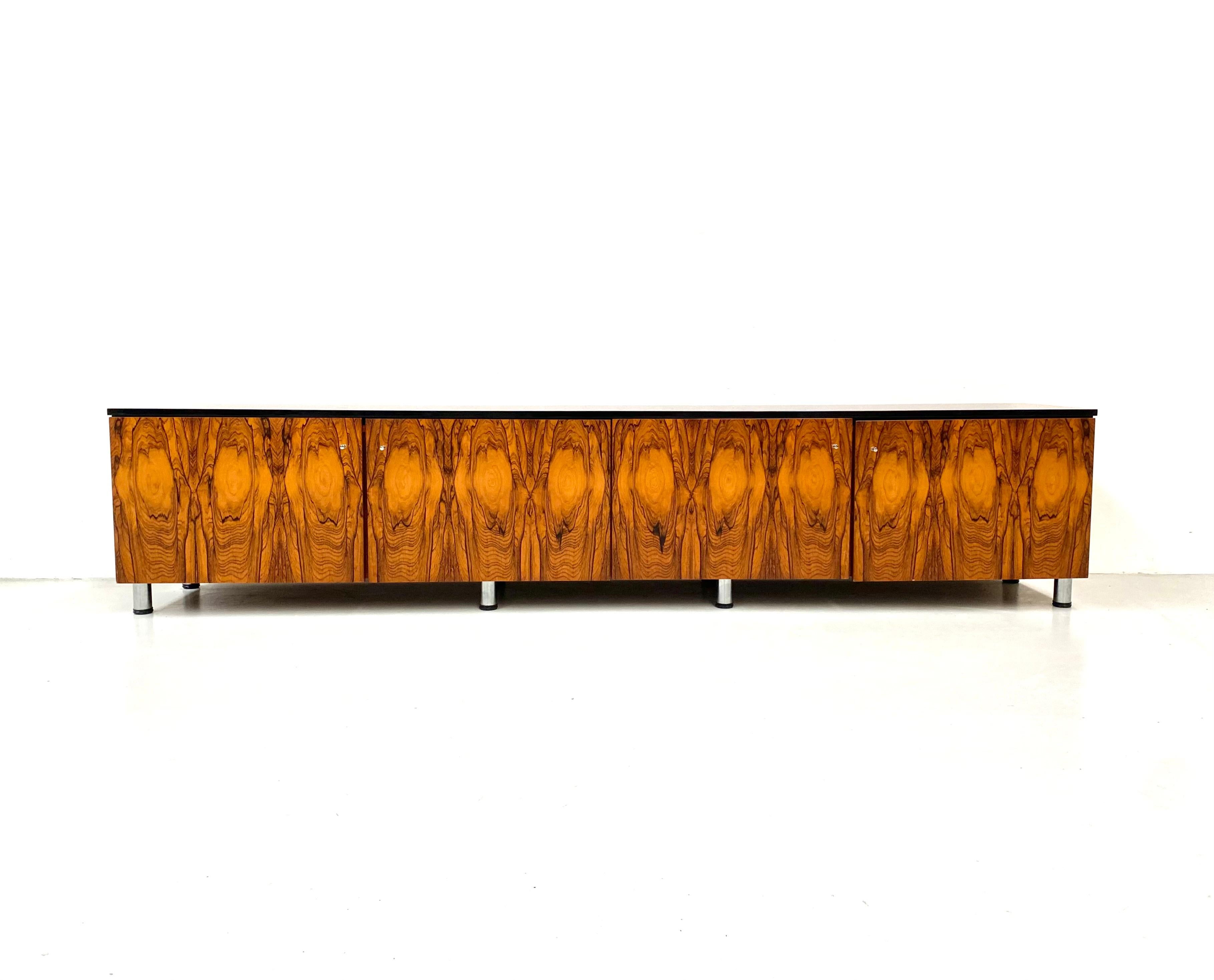 This extra long sideboard or rather lowboard was purchased by us in Germany. The owner bought the piece of furniture in the 1960s in a specialty store in Berlin.
The sideboard has a special repeating drawing in the walnut wood. There are two large