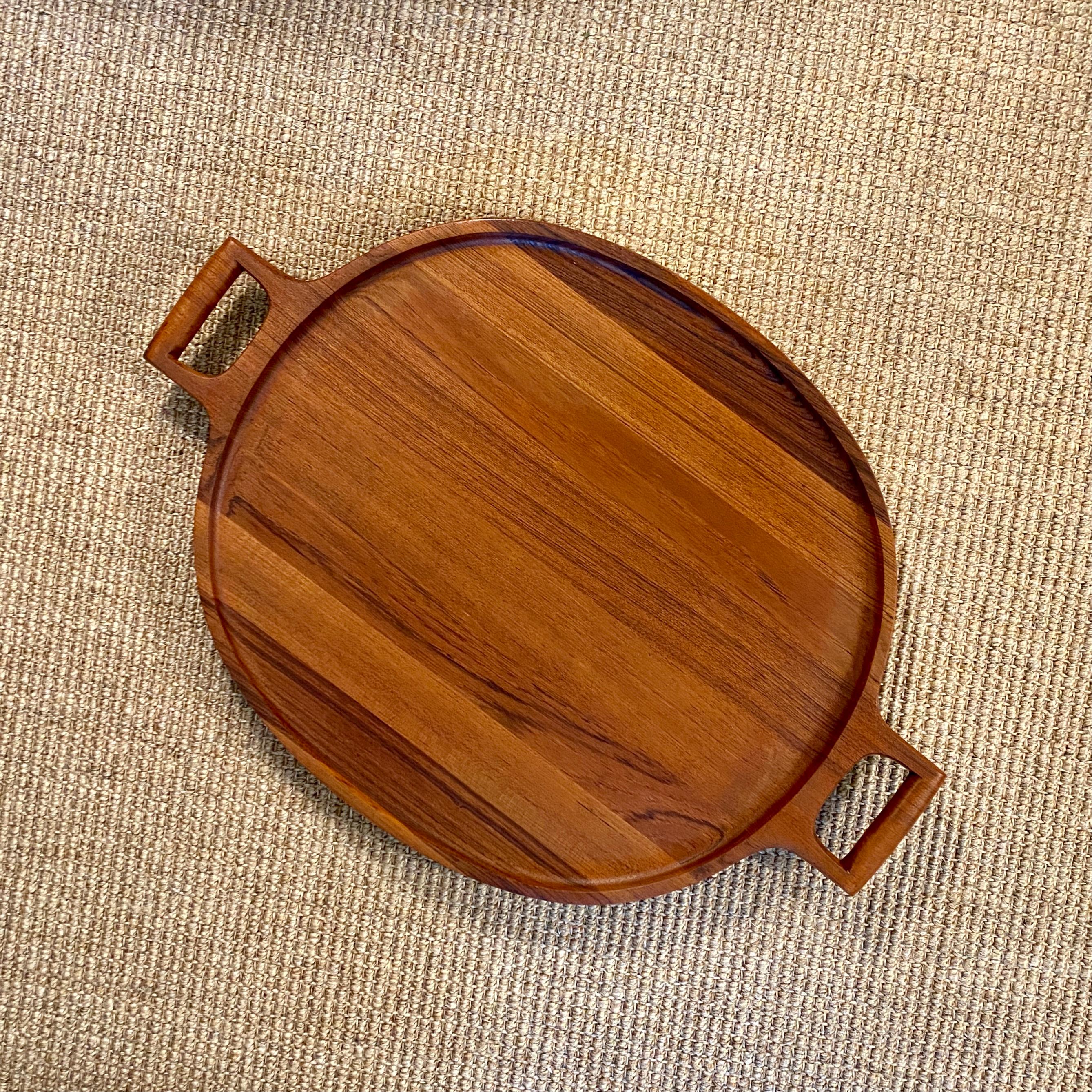A large handled teak tray designed by Jens Quistgaard for Dansk. On the bottom the tray has the early three duck Dansk logo which dates the tray to the 1960s. The tray measures approximately 26 3/4 inches wide, 19 inches deep and is 1 1/2 inches