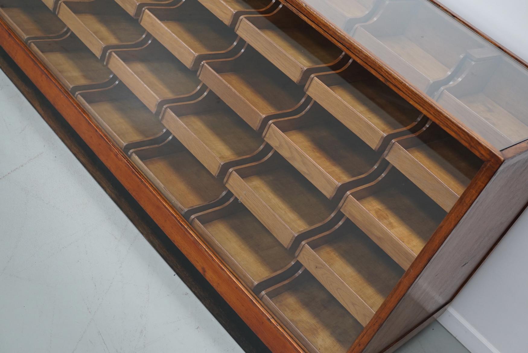This oak haberdashery shop counter dates from the 1950s and was made in Groningen by H.Venema. It features a solid wooden frame, a glass casing and 45 drawers in oak with recessed handles.