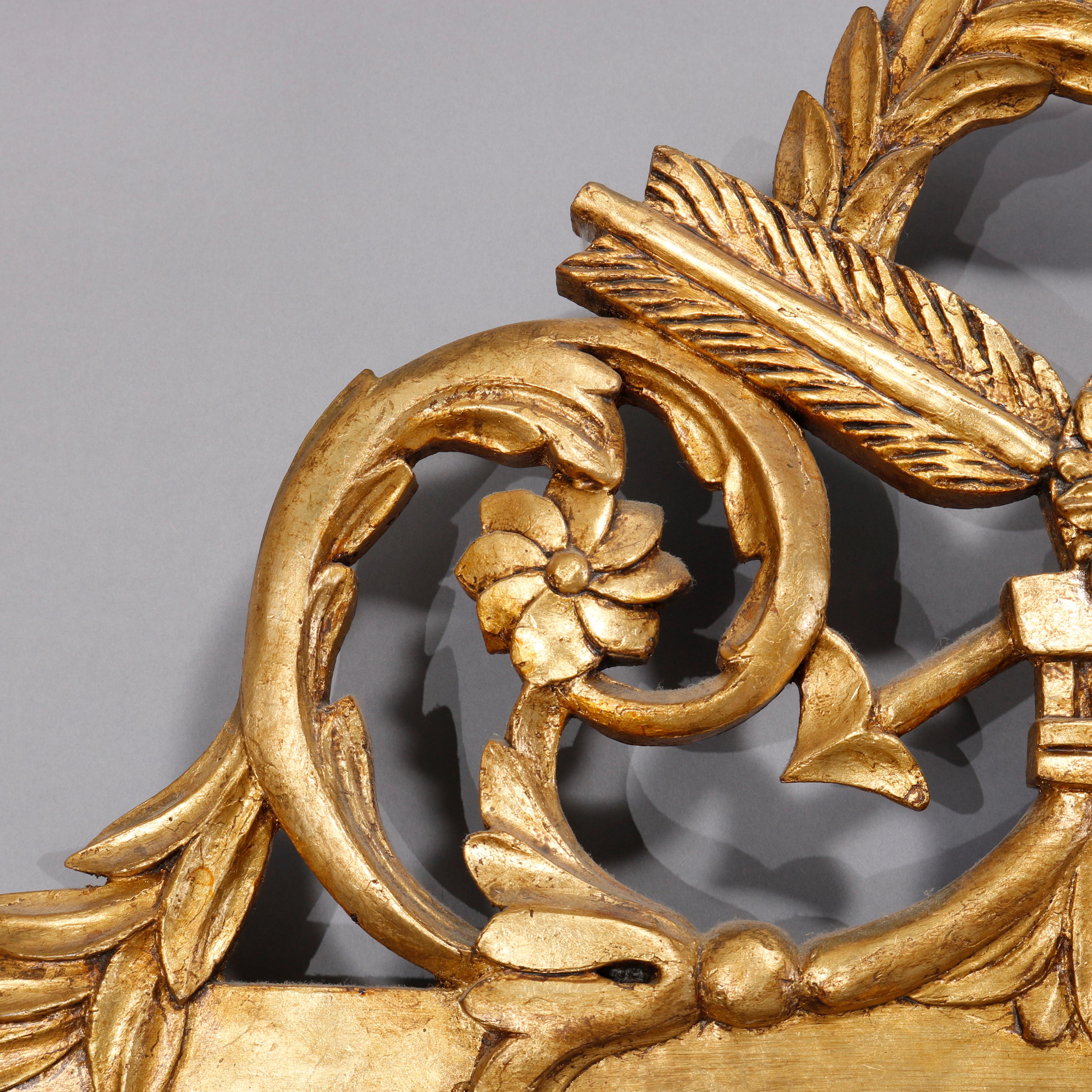 Un grand miroir mural Louis XVI français offre un cadre en bois doré avec une crête percée avec un symbole central de victoire avec une couronne ayant des éléments flanqués de volutes et de fleurs, 20ème siècle
 
Mesures : 51.75