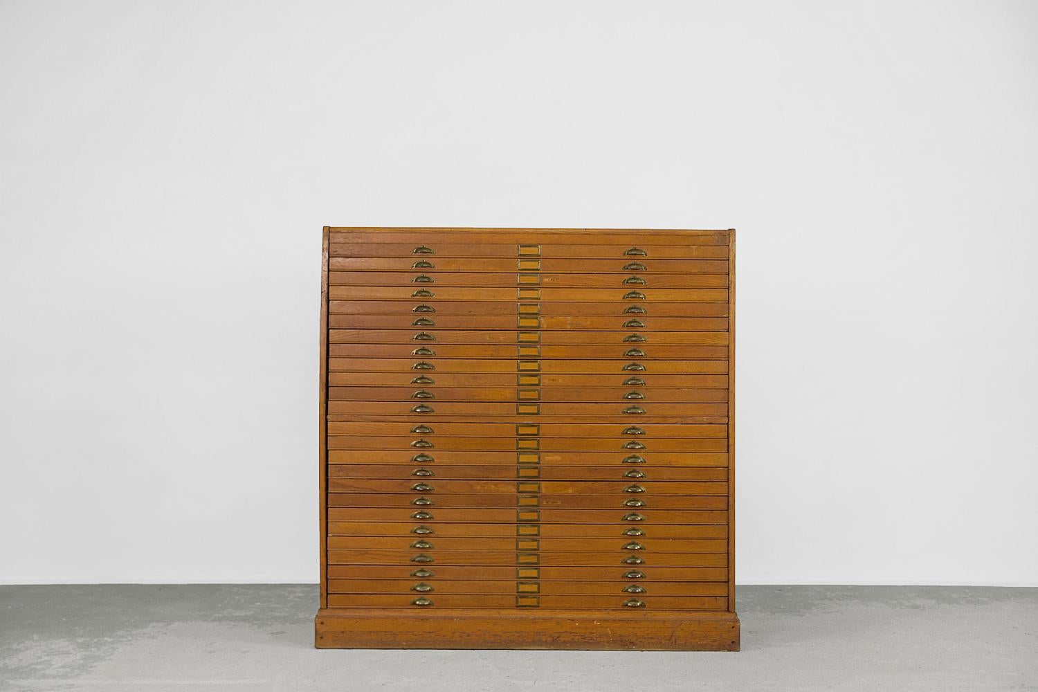 This large, industrial catalog cabinet with multiple flat drawers was made during the 1930s and comes from Artist's Atelie. It is made of high-quality oak wood, which is considered a royal material. Piece of furniture made of oak looks very good