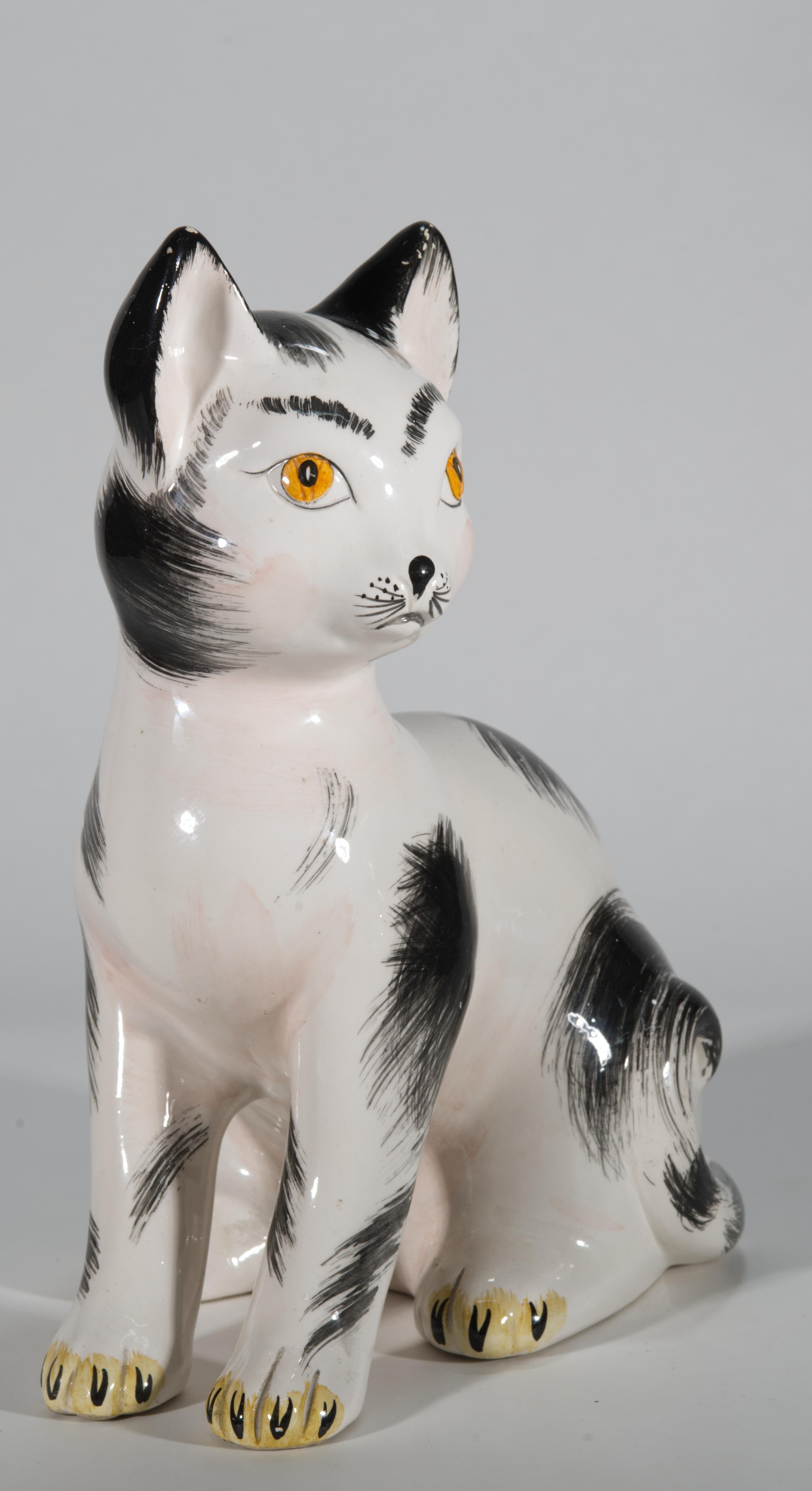  La grande scultura in ceramica raffigura un gatto o un gattino soriano, seduto con la testa girata di lato. La statuetta è decorata con uno smalto di maiolica con segni neri dipinti a mano su sfondo bianco, simile a un cappotto smoking, ma con una