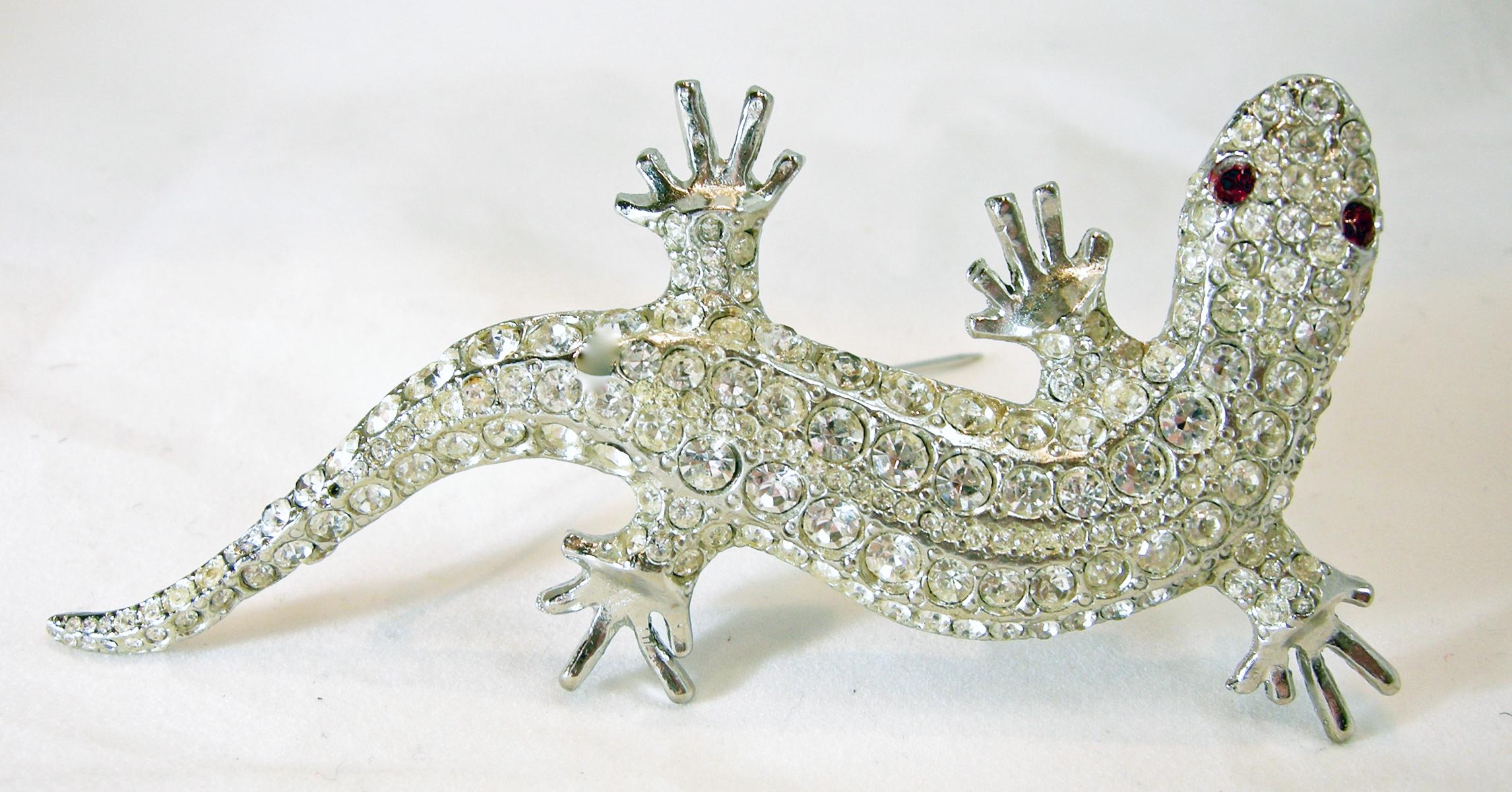 This vintage Kirks Folly salamander brooch has clear crystals throughout its body and red crystal eyes in a silver tone setting.  In excellent condition, this brooch measures 4-1/2” x 2-1/4”.