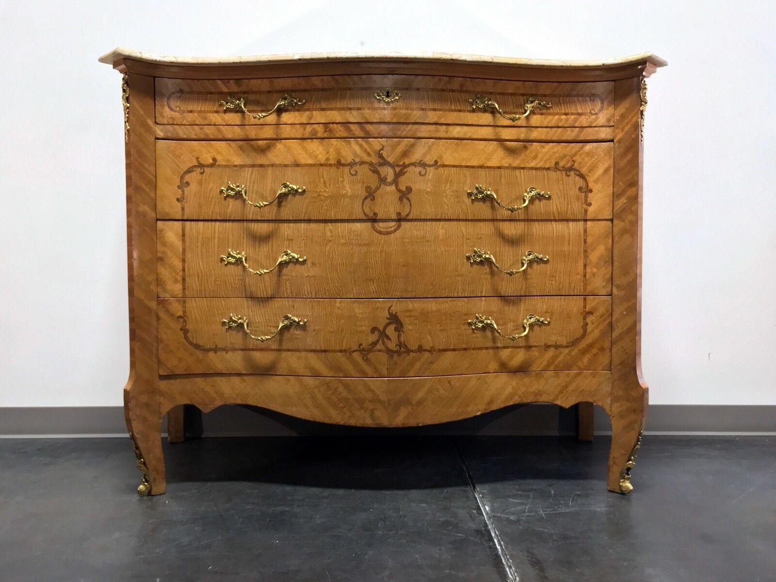 A striking French Provincial Louis XV style large commode chest. Satinwood with ample inlaid marquetry details, serpentine shape, marble top, brass hardware and ormolu mounts. Features four drawers of dovetail construction, with top drawer having an