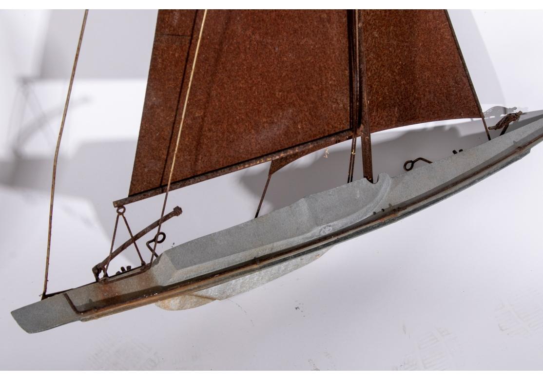 Large Sailboat sculpture for wall Mount in mixed metal. A sailboat with a gray metal hull and iron sails and rigging. With projecting loops on the back for hanging. 

L. 33