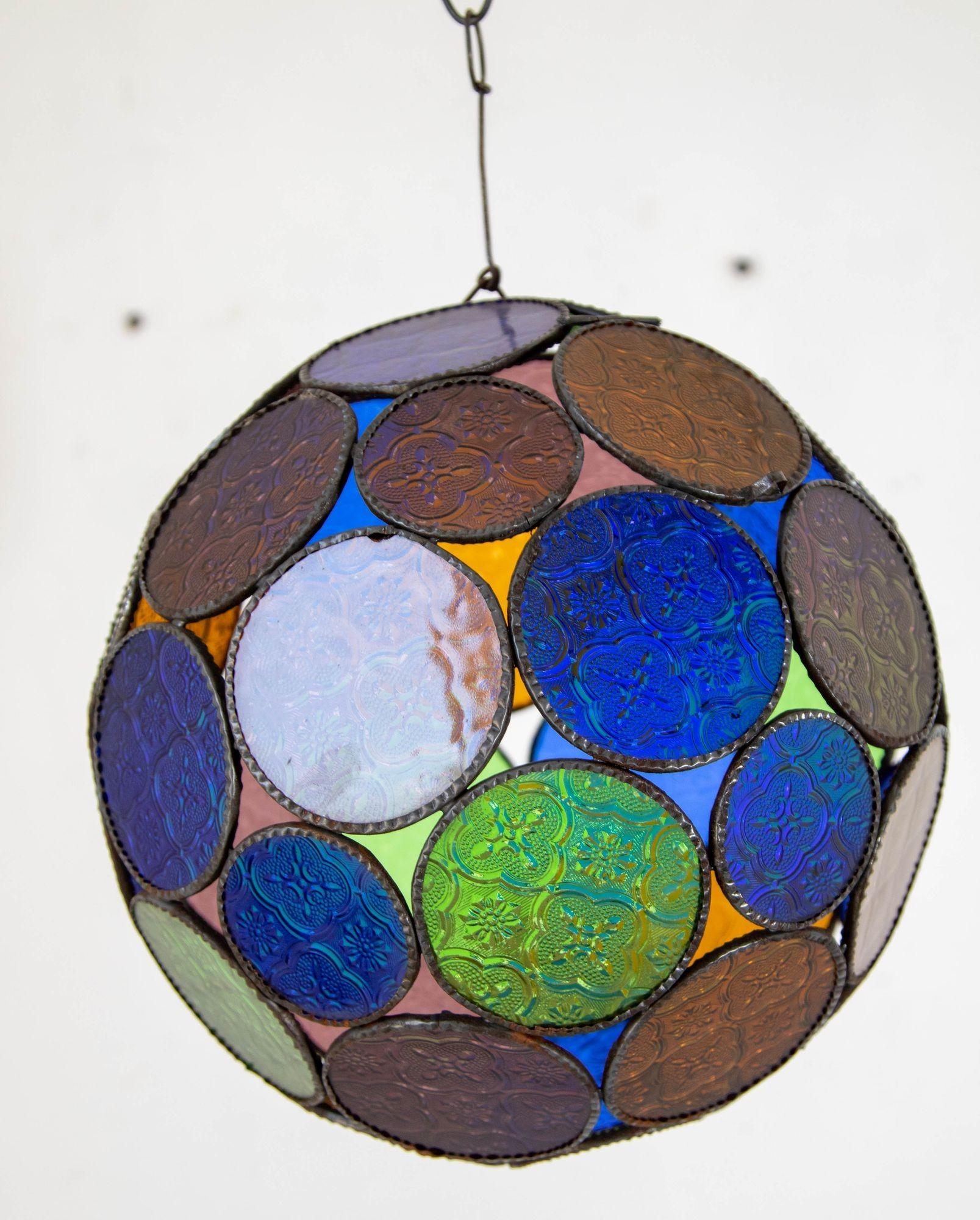 Handgefertigte mehrfarbige marokkanische Glaslaterne oder maurische Pendelleuchte im Vintage-Stil.
Mehrfarbiges geformtes Glas in blau, grün, lavendel und bernsteinfarben mit maurischen Designkreisen, die in einer Lampe im Orb-Stil vereint sind.