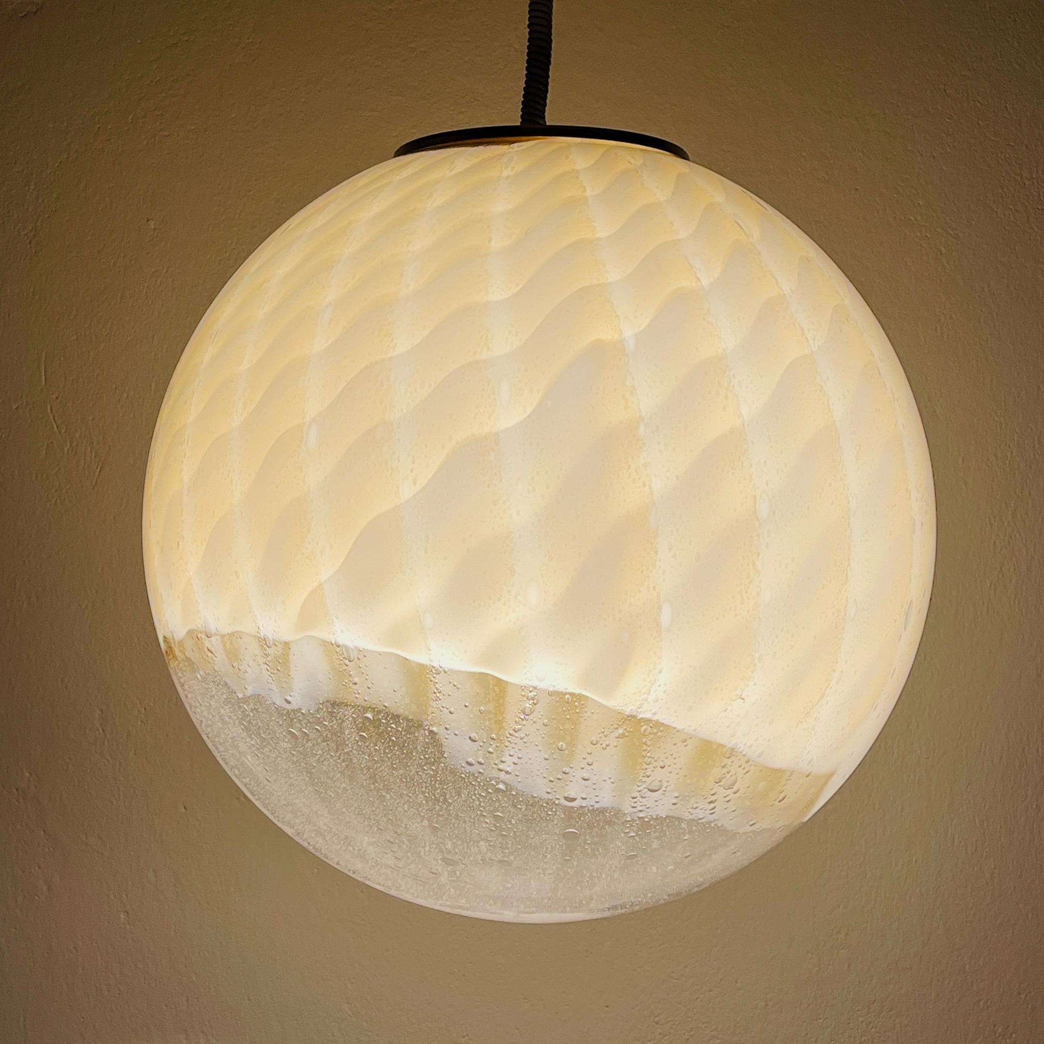 A magnificent large glass globe pendant light by VeArt from Murano was made in Italy in the 1960s. Transparent at the bottom and beige hand-blown Murano glass with visible stripes and bubbles is stunningly gorgeous when lighted. Model in the Paolo