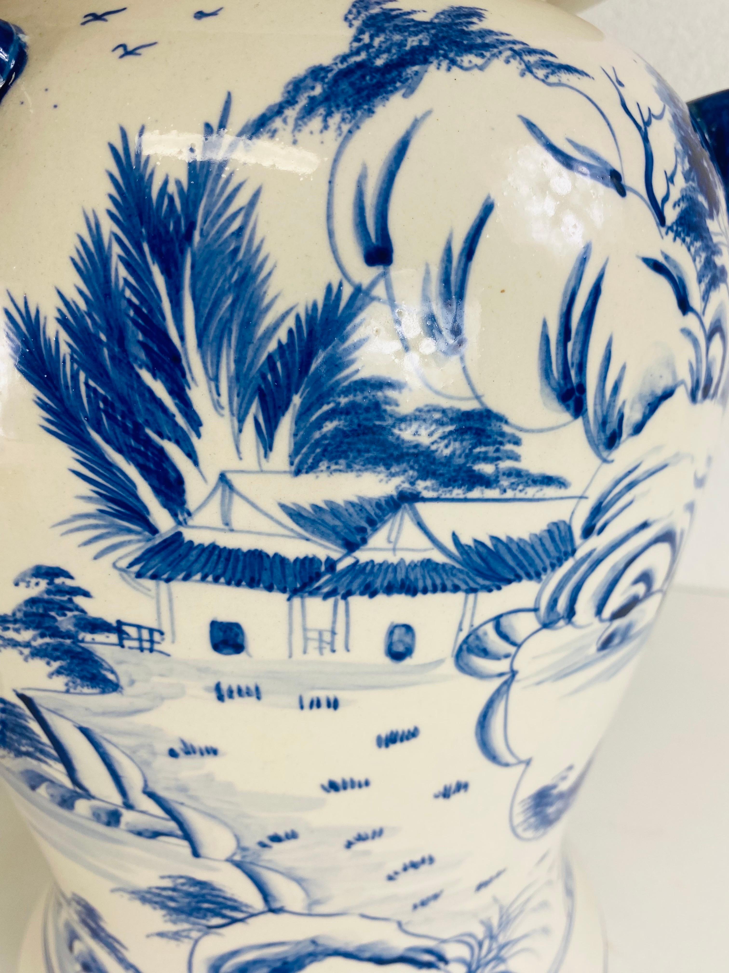 Il s'agit d'une paire de jarres chinoises peintes à la main avec couvercles. Cette grande paire de jarres en poterie a un fond de couleur crème avec des décorations de style chinois peintes à la main en bleu cobalt tout autour du service. Les jarres