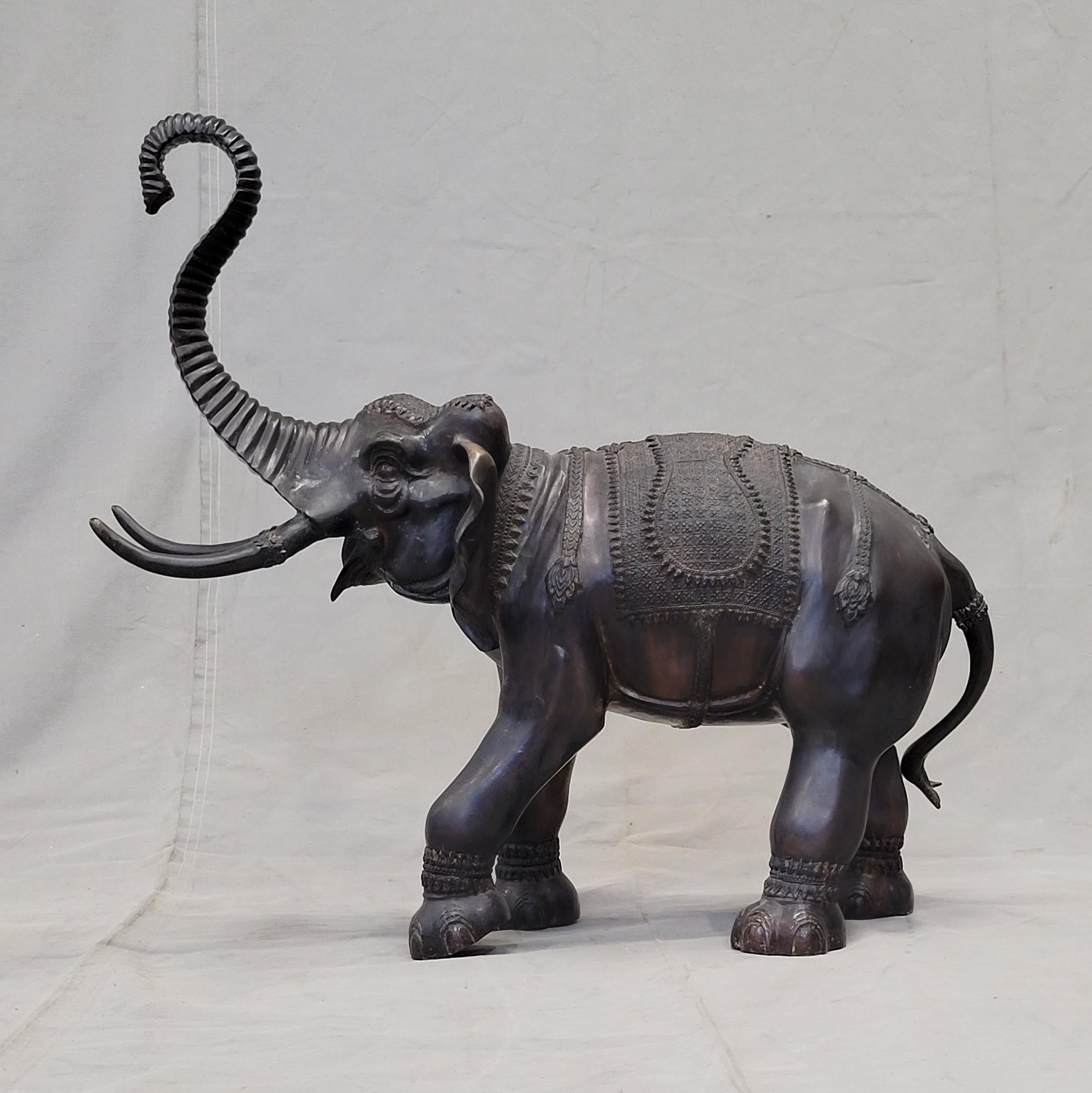 Questo grande e affascinante elefante vintage in ottone, forse bronzo, patinato, si erge con la proboscide sollevata e le zanne distese. È firmato 