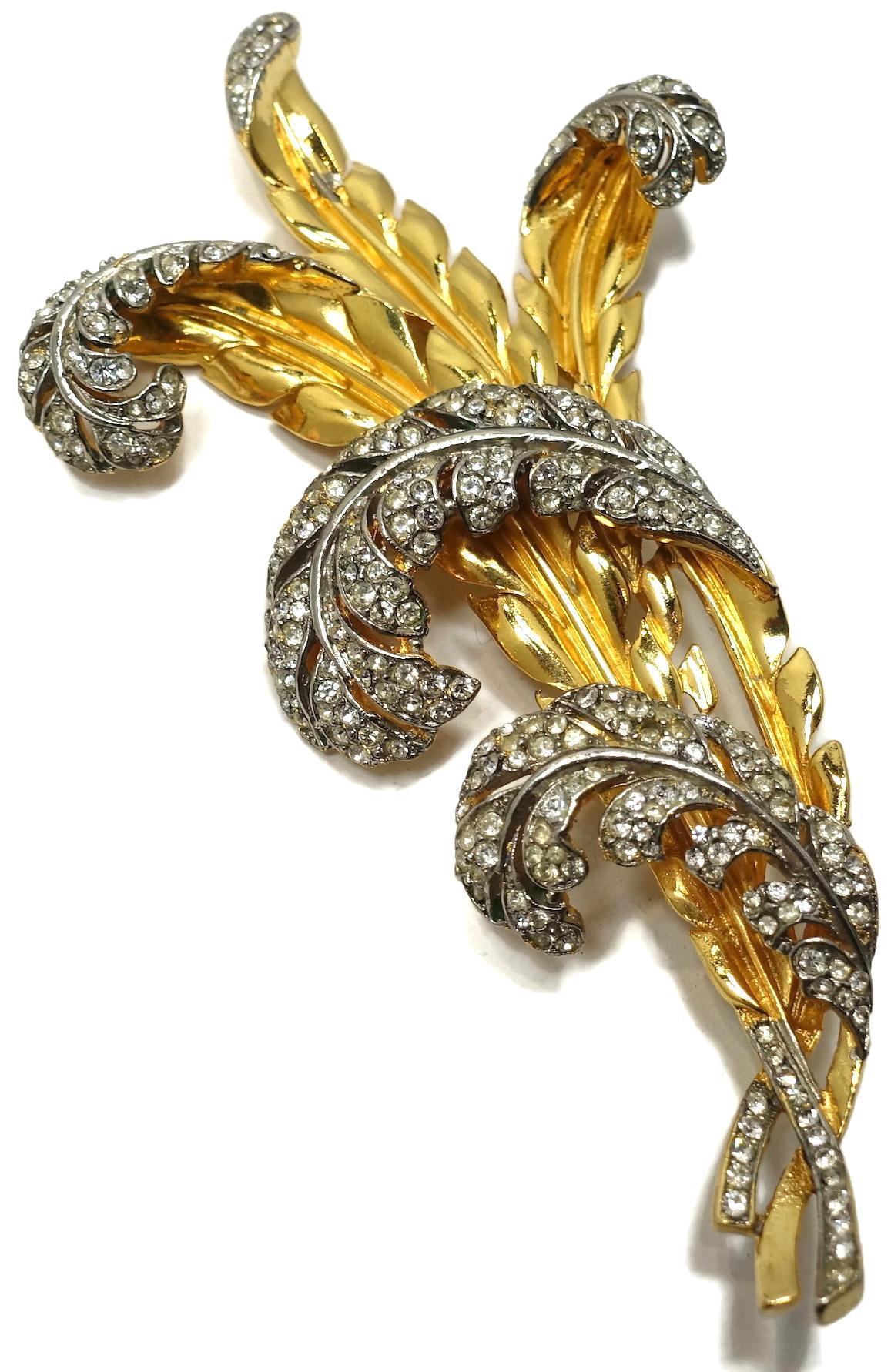 This vintage retro brooch is an unsigned Trifari. It has crystal feathers on gold tone ornate stems.  In excellent condition, this brooch measures 3” x 2-5/8”.