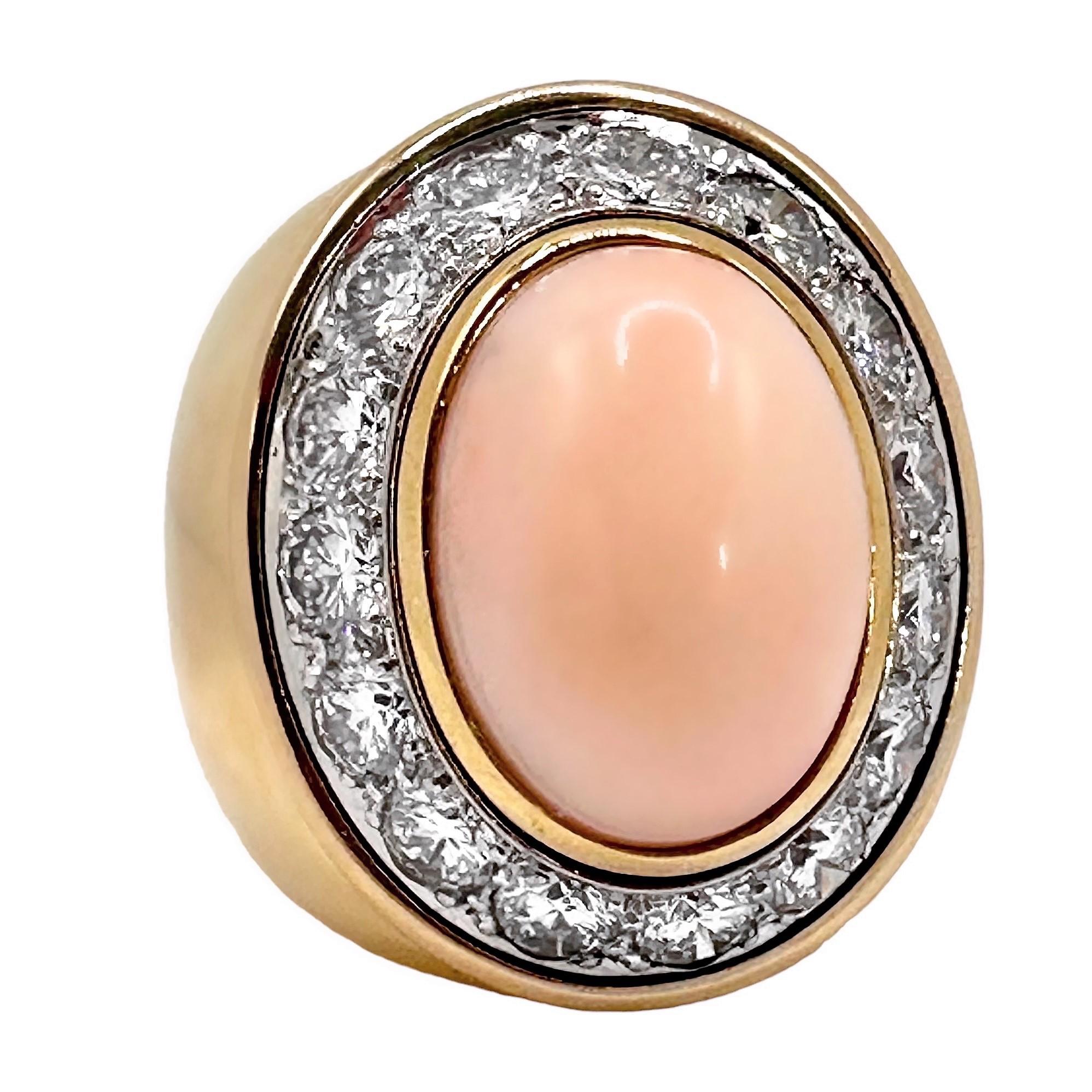 This very large scale, vintage 18K yellow gold ring has, at it's center, one oval shaped, bezel set,  20mm by 14mm angel skin coral cabochon. Surrounding the cabochon are fifteen brilliant cut diamonds having a total approximate weight of 5.00ct of