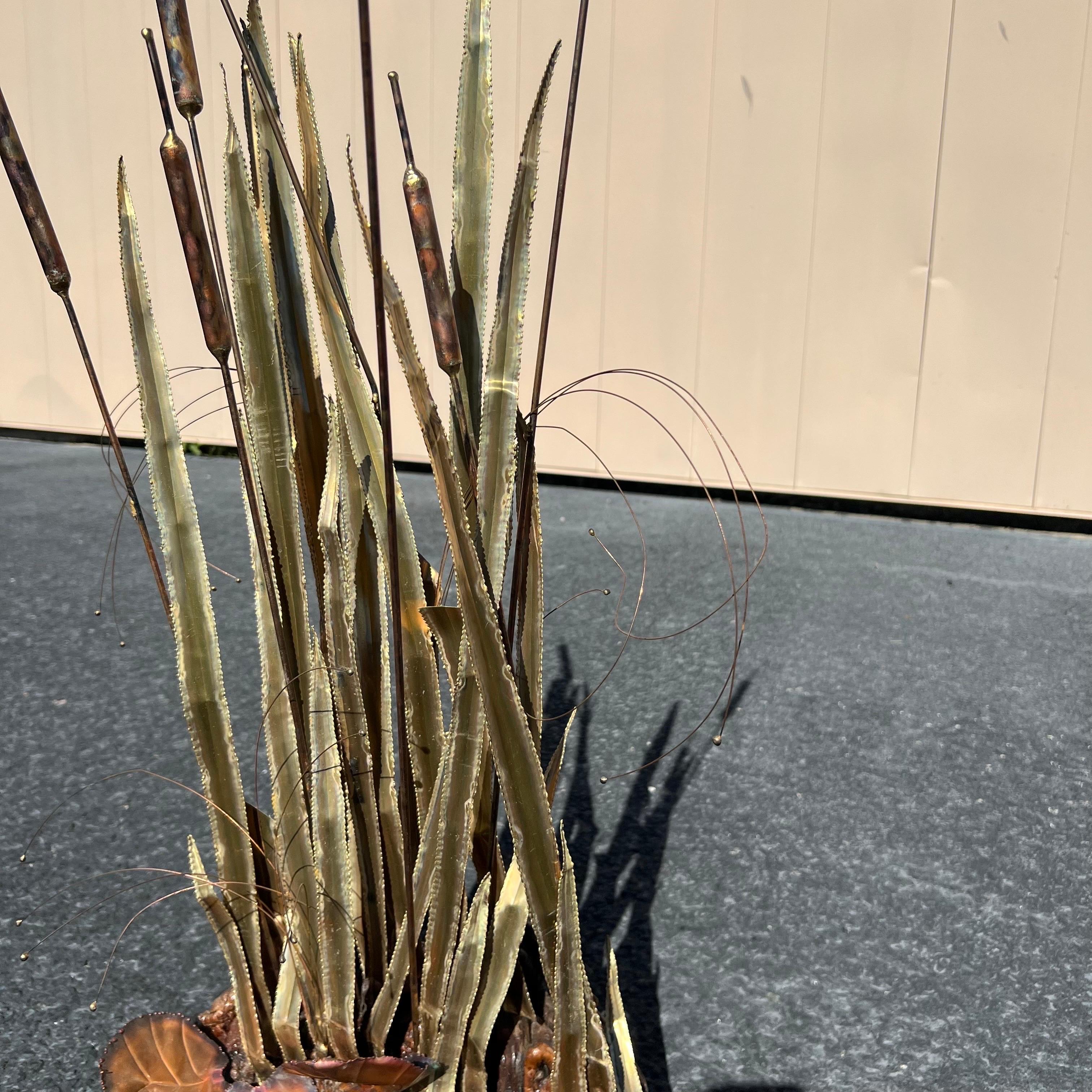 A beautiful brutalist mixed metal sculpture on a Burled wood base.  It featured 7 cattails in different heights as well as leaves of different heights and shapes.  After C.  Jere.