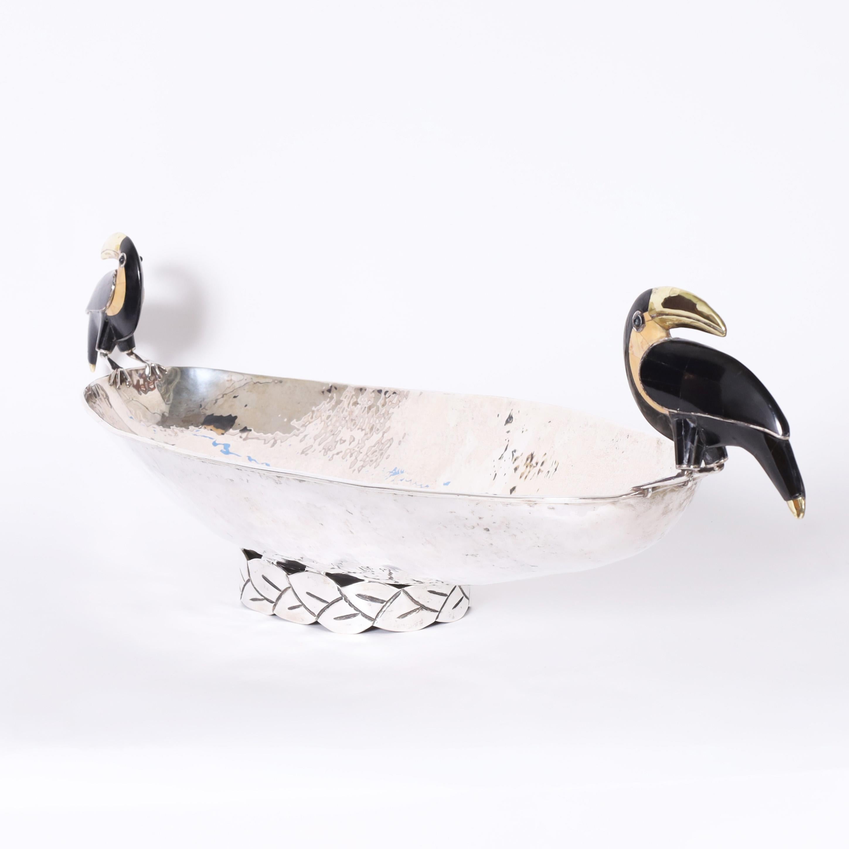 Striking vintage bowl with an elongated form handcrafted in silver plate on hammered copper featuring two stone clad toucans as handles. Signed Emilia Castillo Mexico on the bottom.
