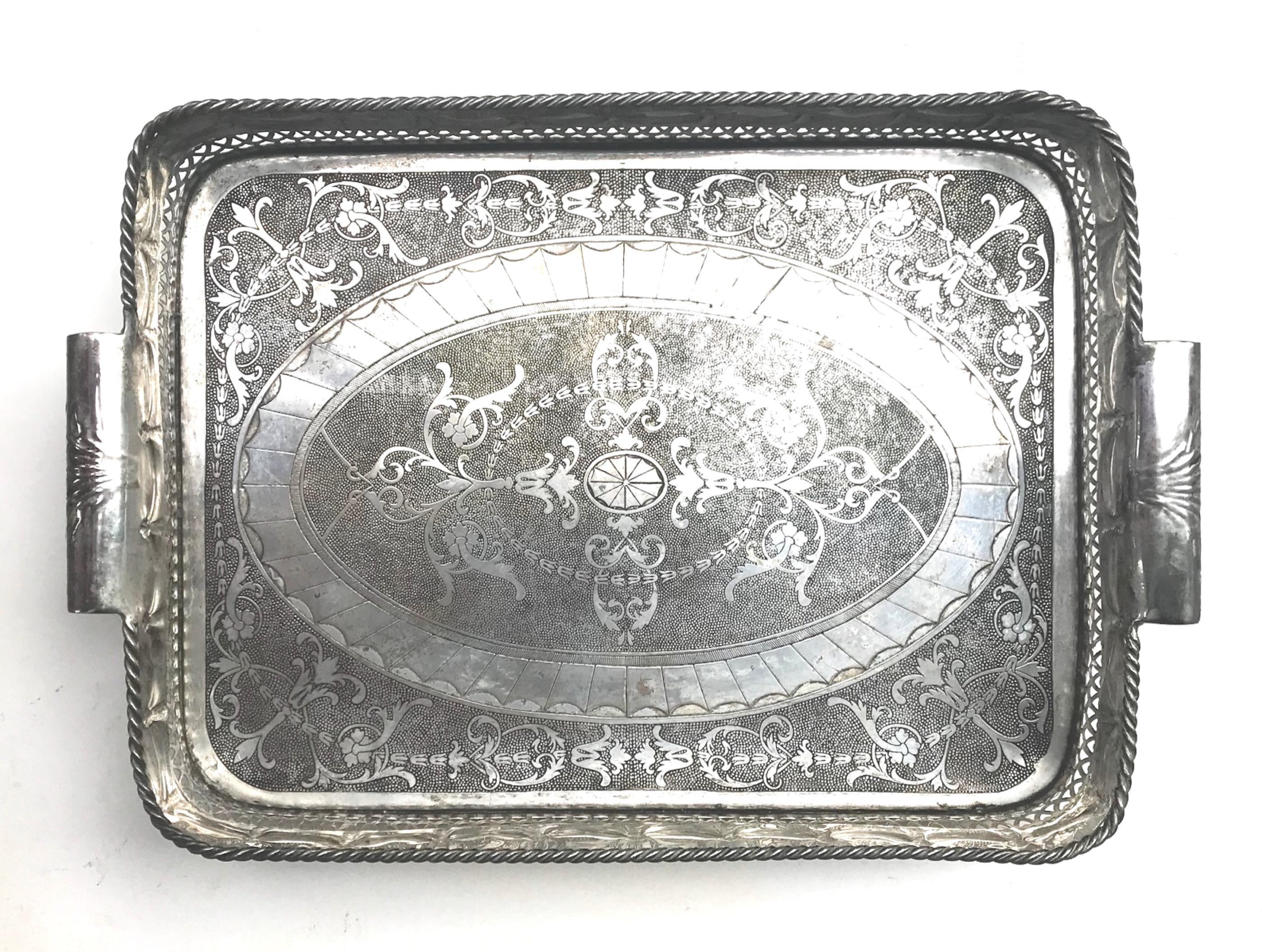 Vintage large silver plated Anglo-Indian Butlers gallery tray

Magnificent large silver plated butlers tray. The base is engraved in a beautiful pattern. It features a highly stylized pierced gallery with scrolled handles at either side. This