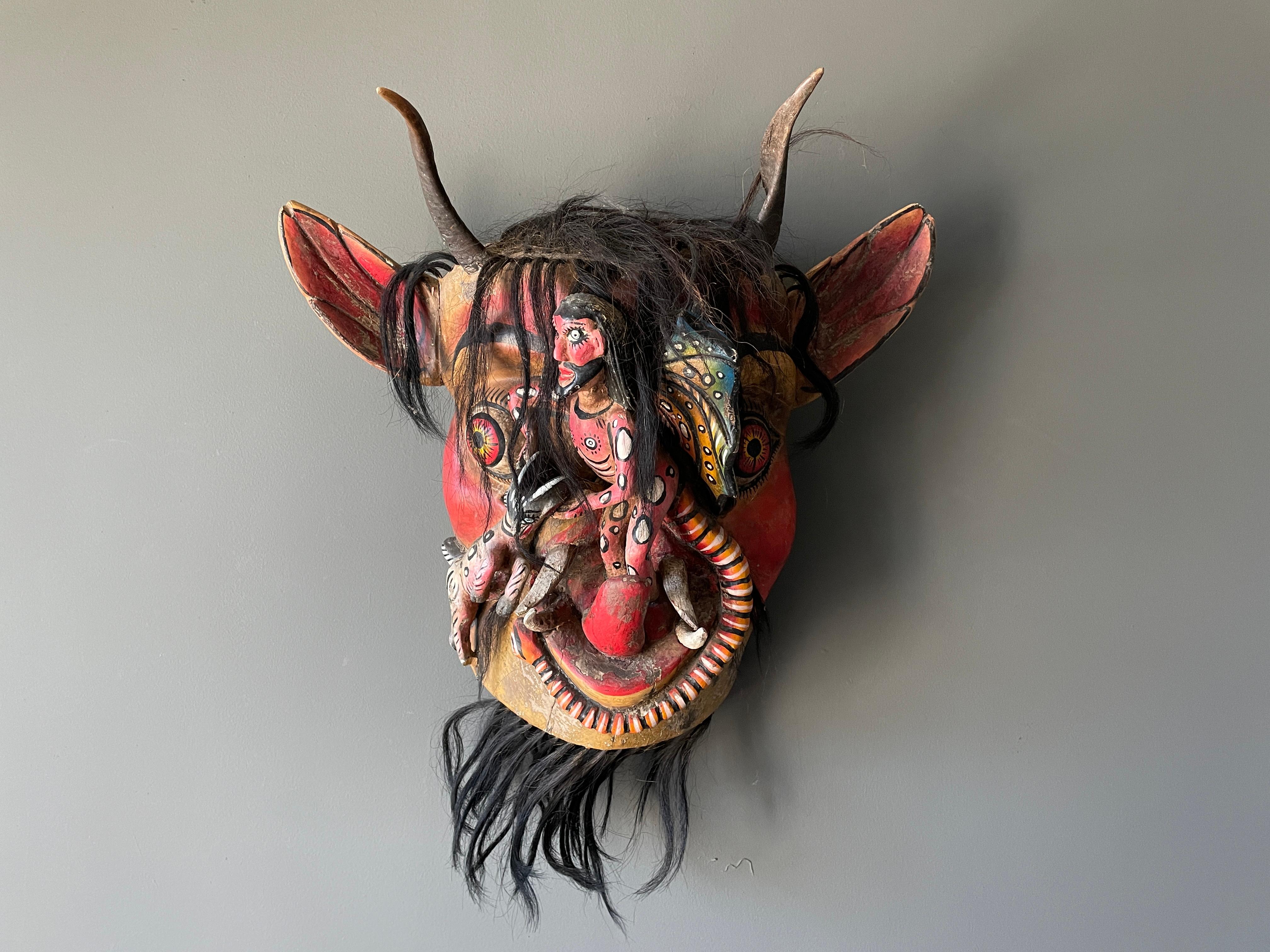 Vintage large size hand carved tribal mask. Deep, vibrant colors with integrated goat, snake and human accents. Also features real animal horns. A wonderful accent piece for any room.