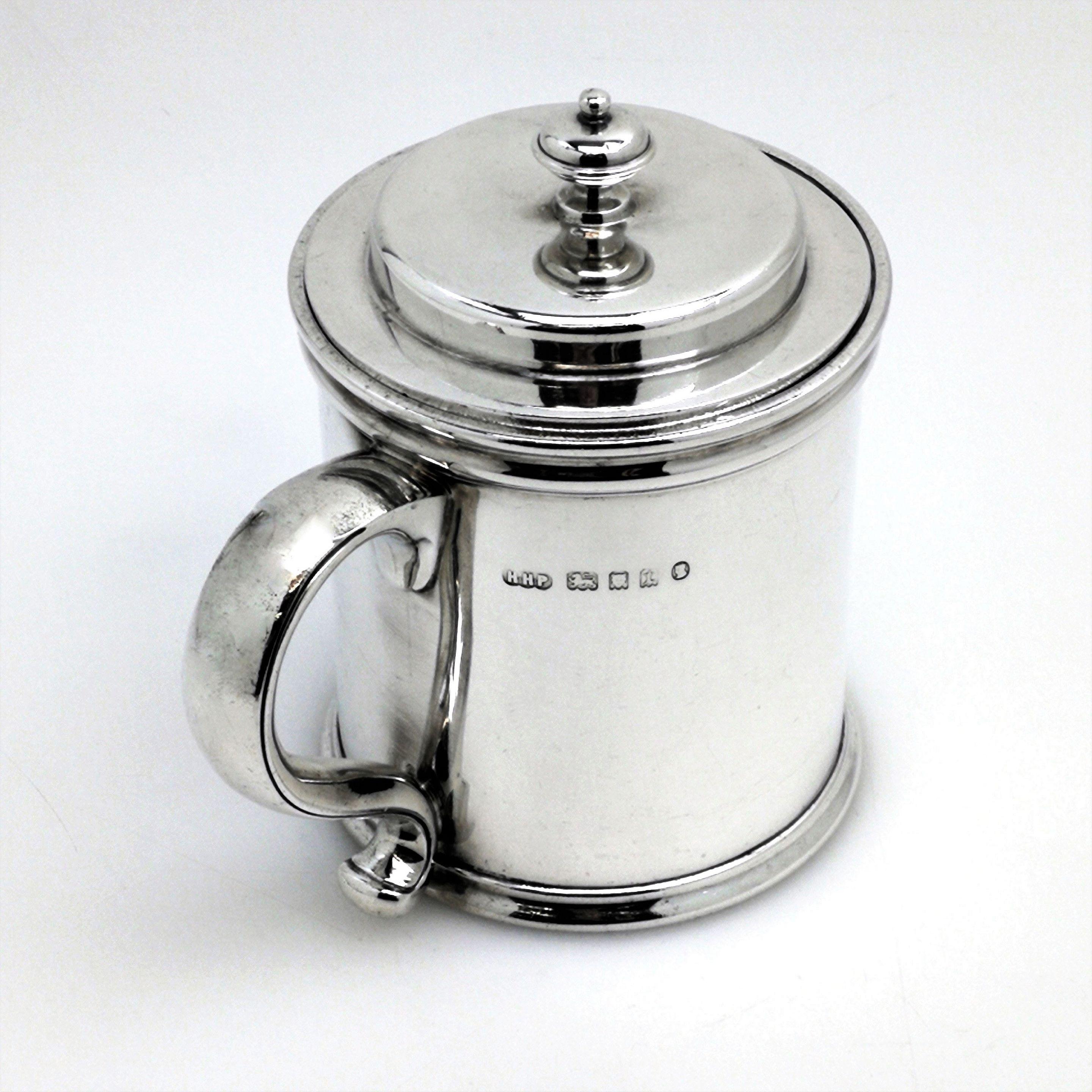 An Impressive antique solid silver preserve jar with a fitted lid and a dark blue removable glass liner. The jar has a classic straight sided design with a scroll handle, and features a small engraved crest opposite the handle.
 
 Made in London