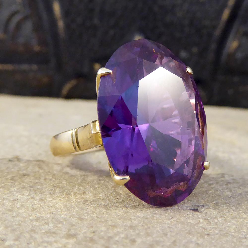 This eye catching ring features a large synthetic Alexandrite stone. Typically an Alexandrite gem has a different colour perception depending on the light and environment, it ranges from a deep purple through to electric blue depending on the stone.