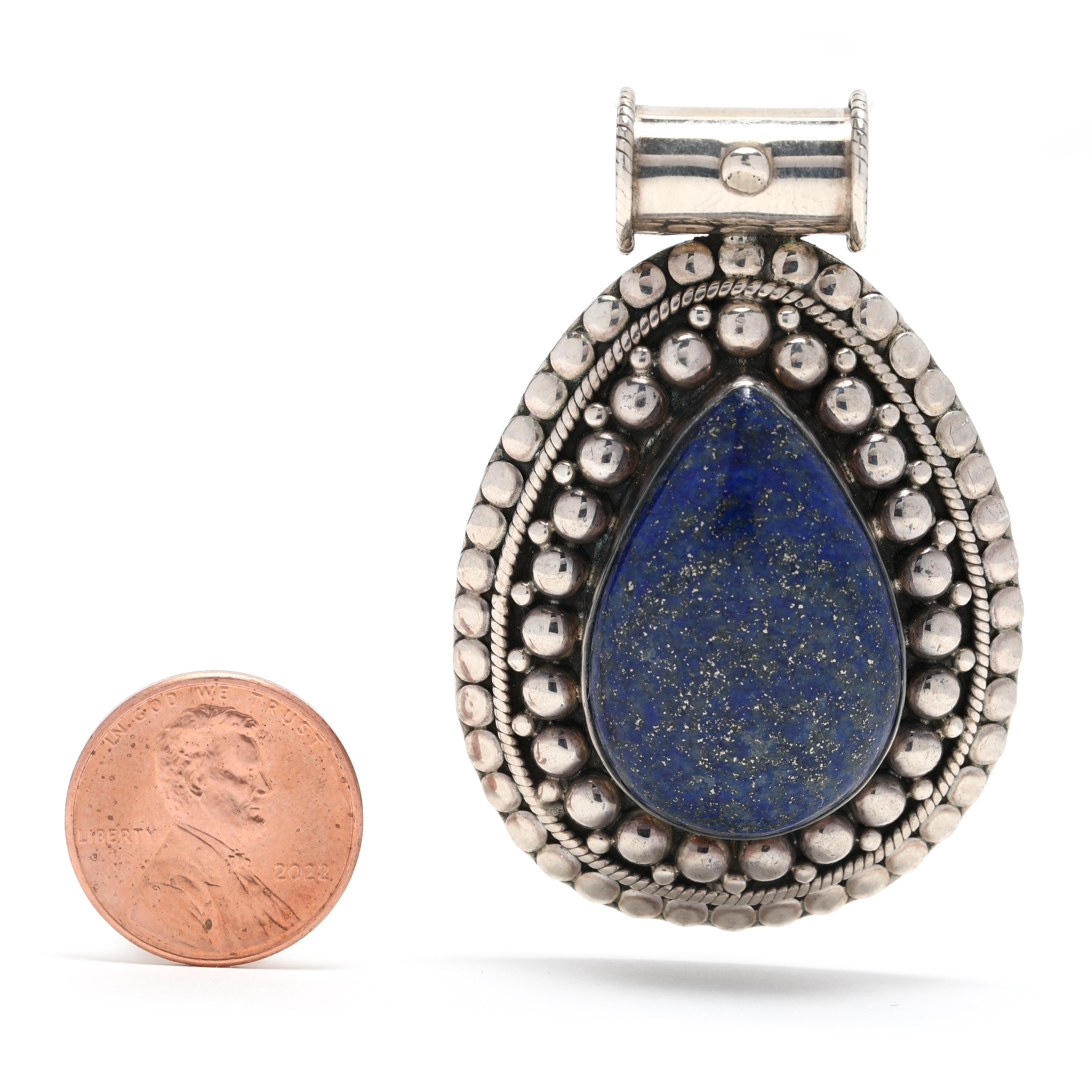 This vintage large teardrop Lapis Lazuli pendant will make a striking statement. The pendant is beaded with natural Lapis Lazuli gemstones and features a sterling silver setting. The pendant measures 2 1/4 inches in length, creating a bold and