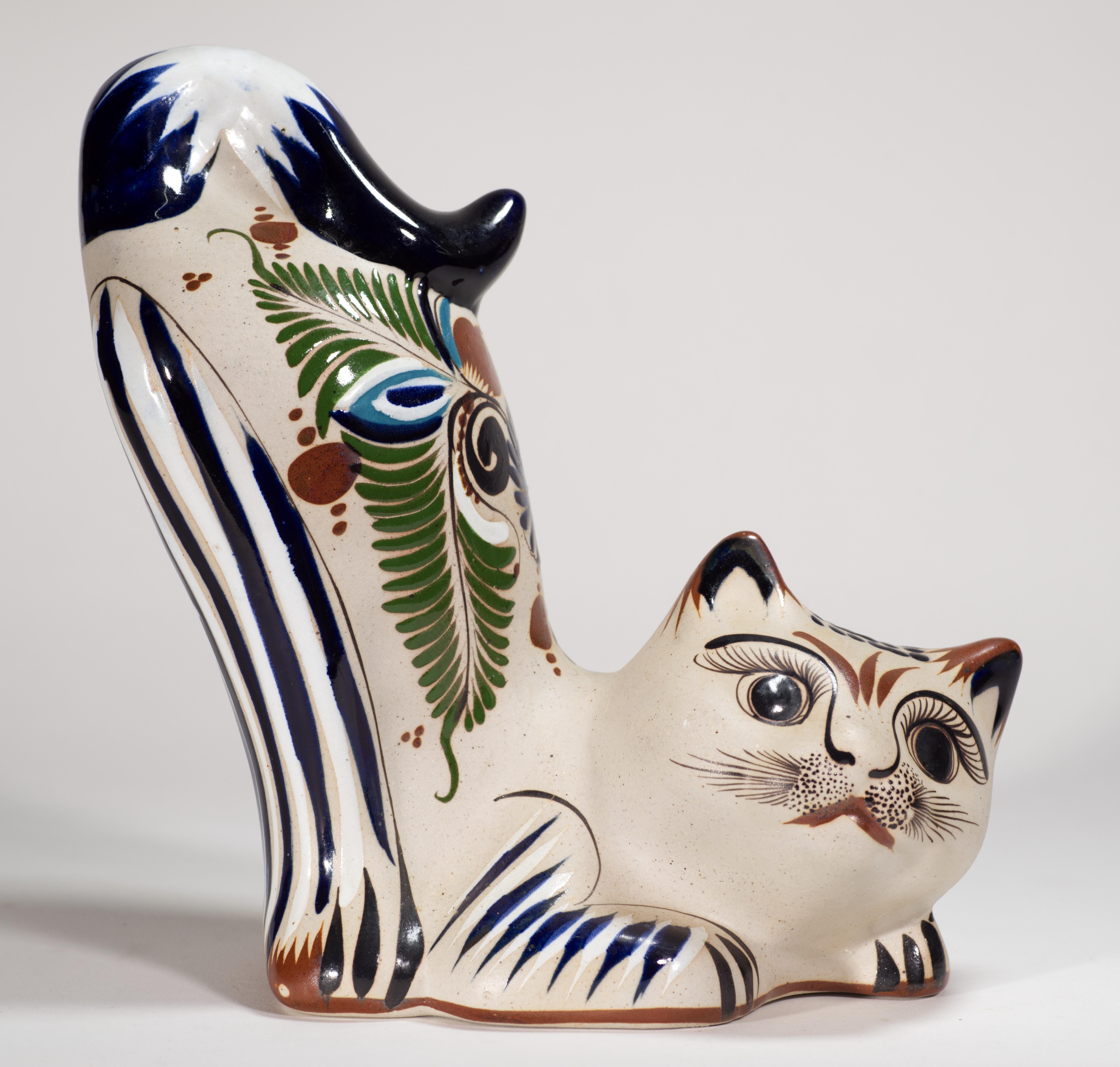  La statuetta di gatto in ceramica Tonala Pottery è decorata con bellissimi disegni geometrici e floreali astratti dipinti a mano nei toni del blu, del verde e del marrone. Variazioni nella consistenza dello smalto e decorazioni meticolosamente