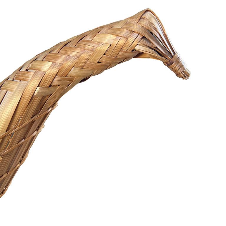 A large woven wicker decorative basket in the shape of a pheasant. This piece will be spectacular for a holiday table to hold breads or pastries. The body of the piece is oval and features a long woven neck. A pointy tail of wood sticks out from the