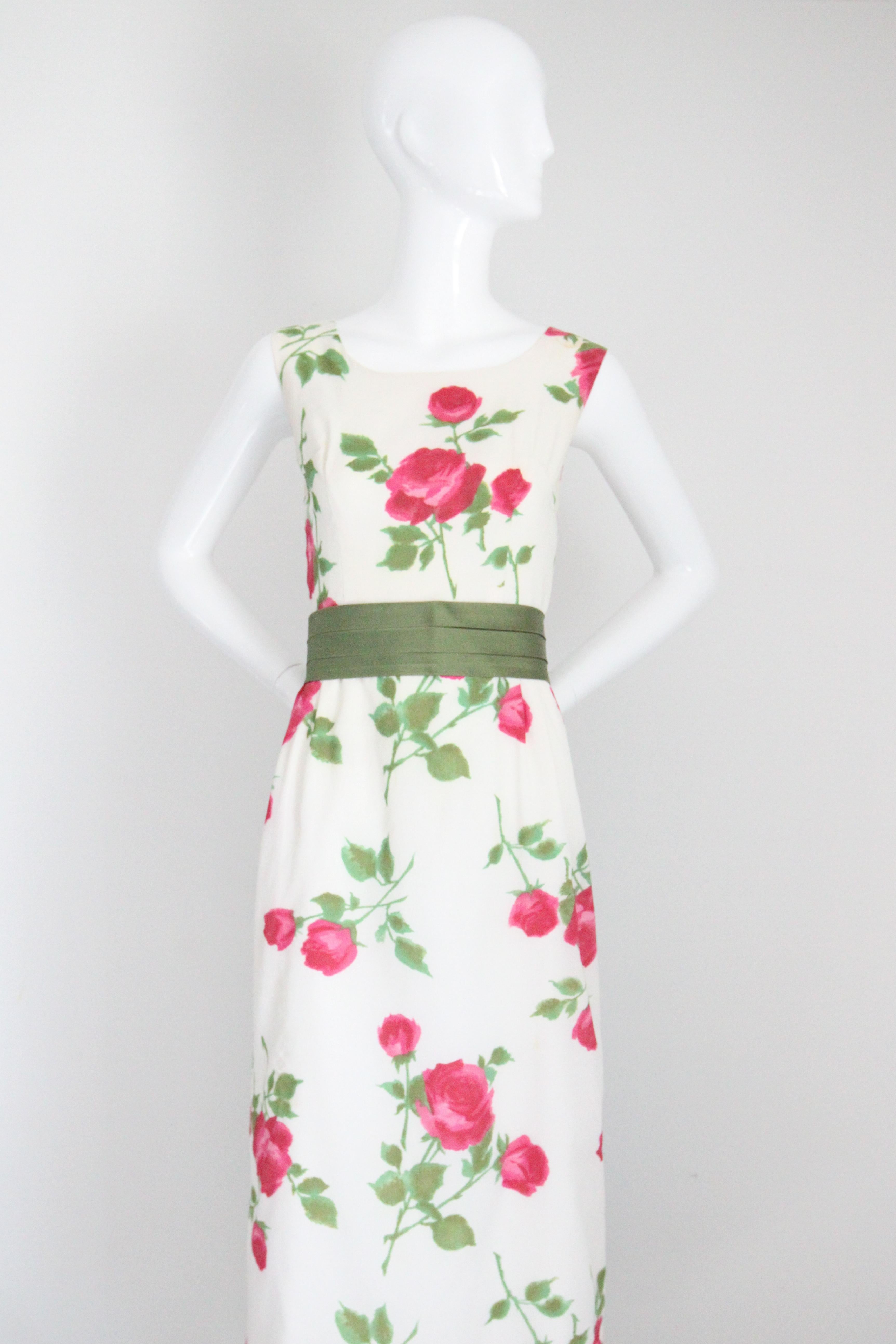 This enchanting late 1950's dress, rendered in a scattered pink rose pattern and set off by a green satin waist belt, is the perfect piece to add to your seasonal cocktail wardrobe. 

The rounded neckline, is framed by medium width shoulder straps,