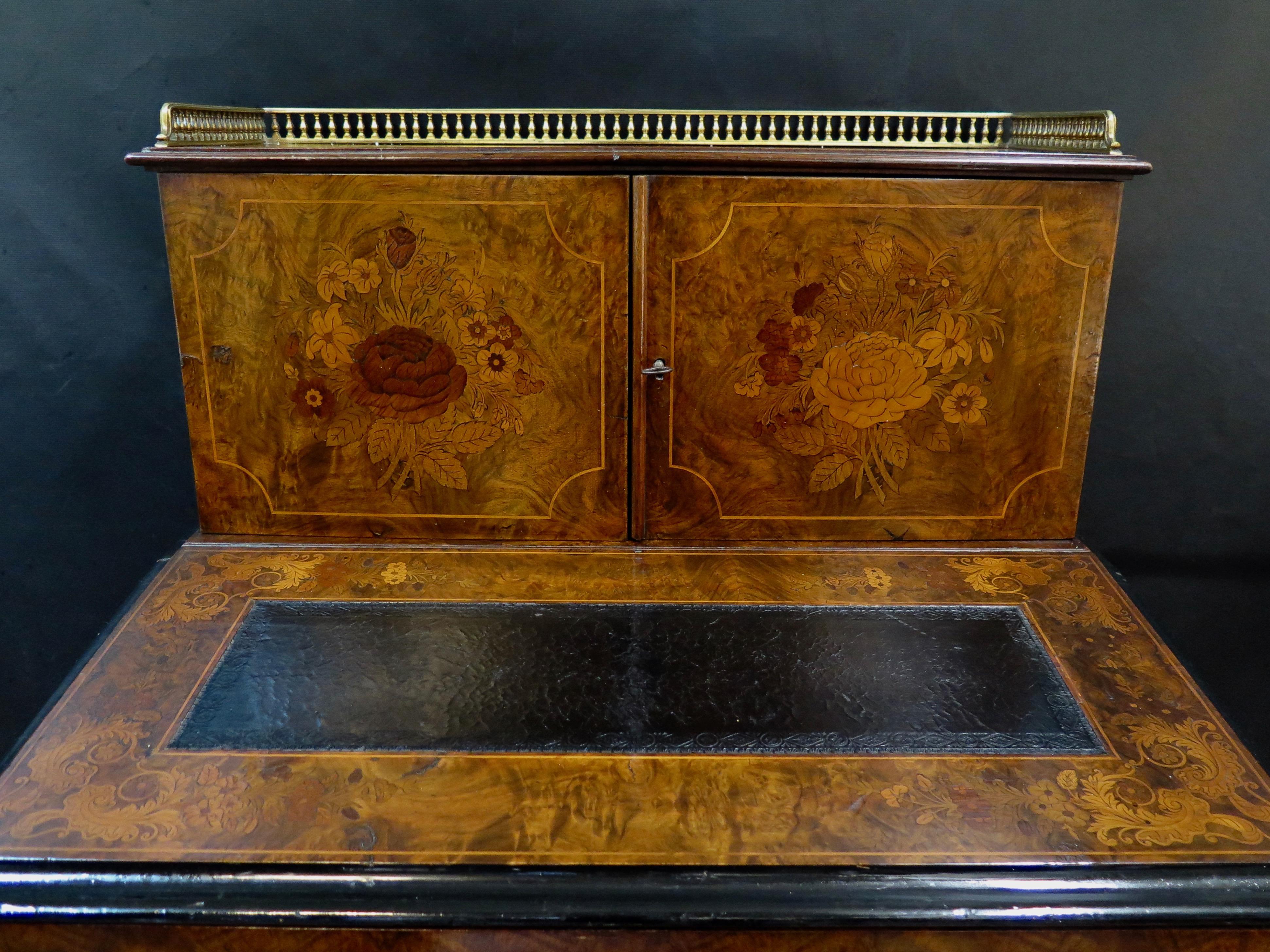 This charming late 19th century French ladies desk is beautifully decorated with handcrafted inlaid decorations in a burl wood. The compact desk has a rectangular black leather insert writing surface in its hinged lid cover
which, when open,