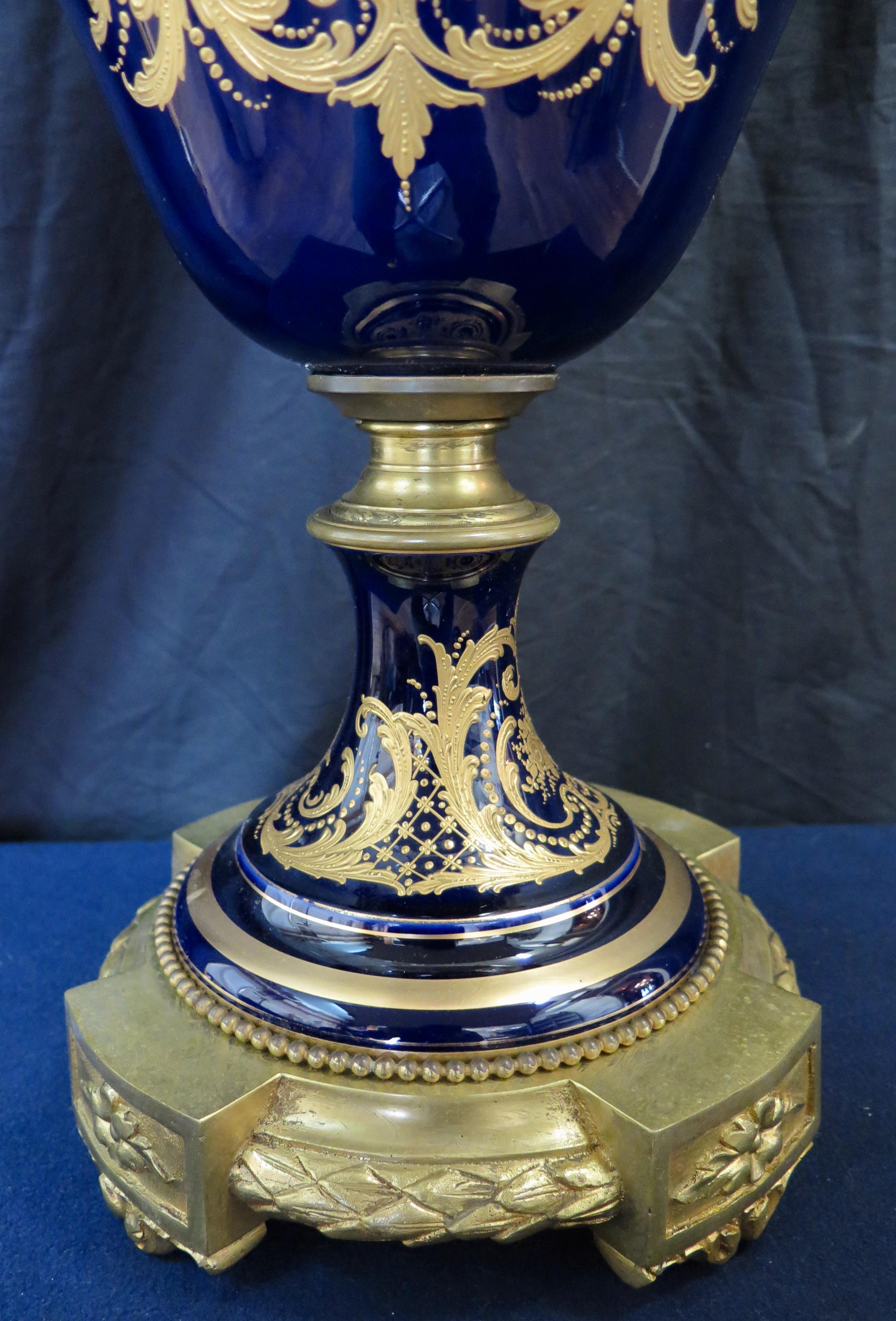 Diese Urne aus französischem Sèvres-Porzellan im Palastformat stammt aus dem späten 19. Jahrhundert. Sie ist kunstvoll verziert und mit vergoldeten Bronzeverzierungen versehen. Die überdachte Urne ist mit tiefblauen Hintergrund mit Hand angewendet