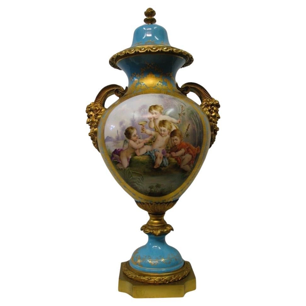 Cette exceptionnelle urne couverte en porcelaine de Sèvres, montée sur bronze doré, date de la fin du 19e siècle. Il est peint en bleu vif, couleur œuf de merle, et rehaussé d'ornements floraux rendus à la main. L'urne est décorée de deux grands