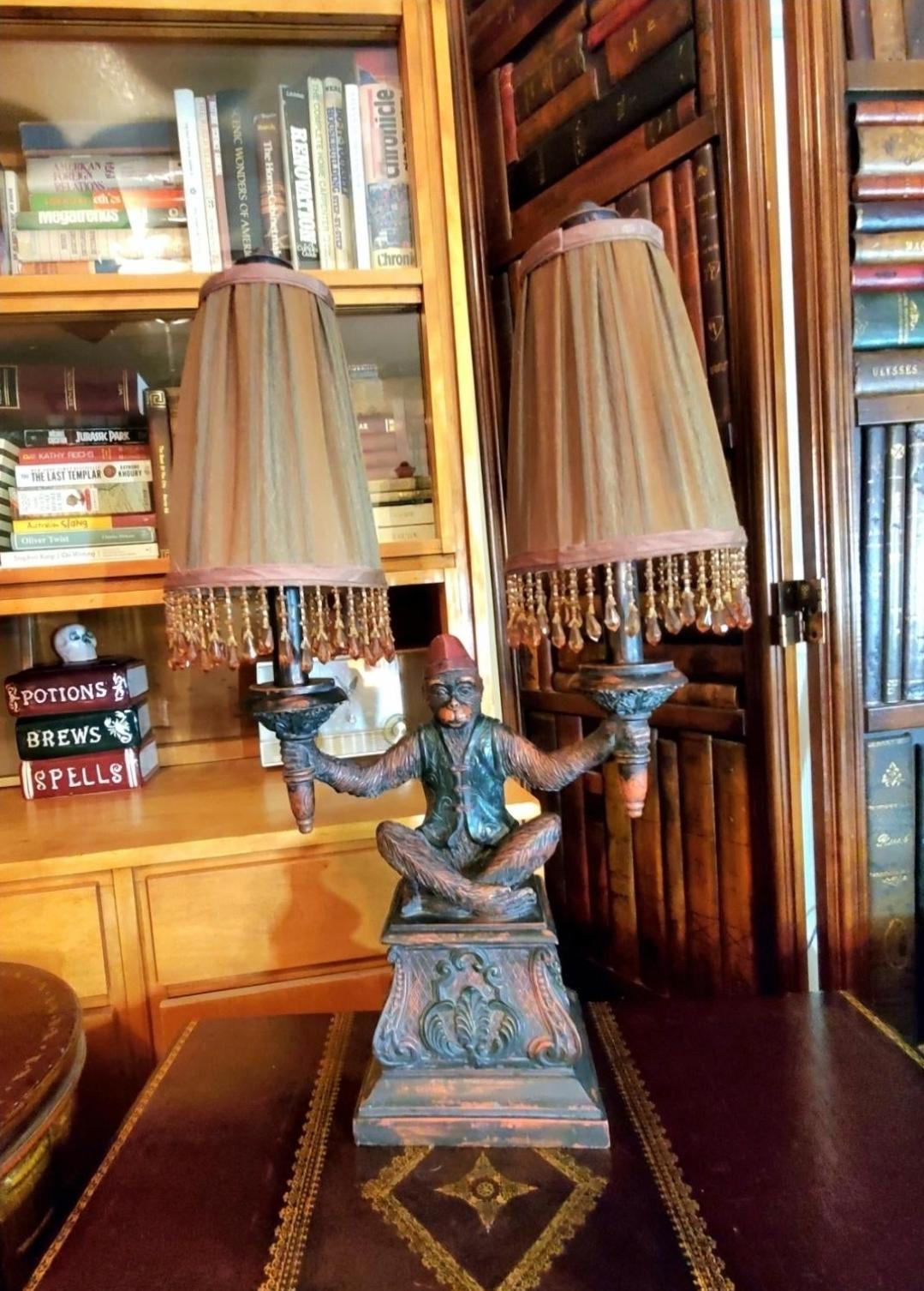 MAITLAND SMITH FIGURAL MONKEY LAMP.
The bellhop monkey is holding two urn form torches.
Beaded, ruched lampshades.
Ornately carved.
Light control is on the cord.
Height 25
